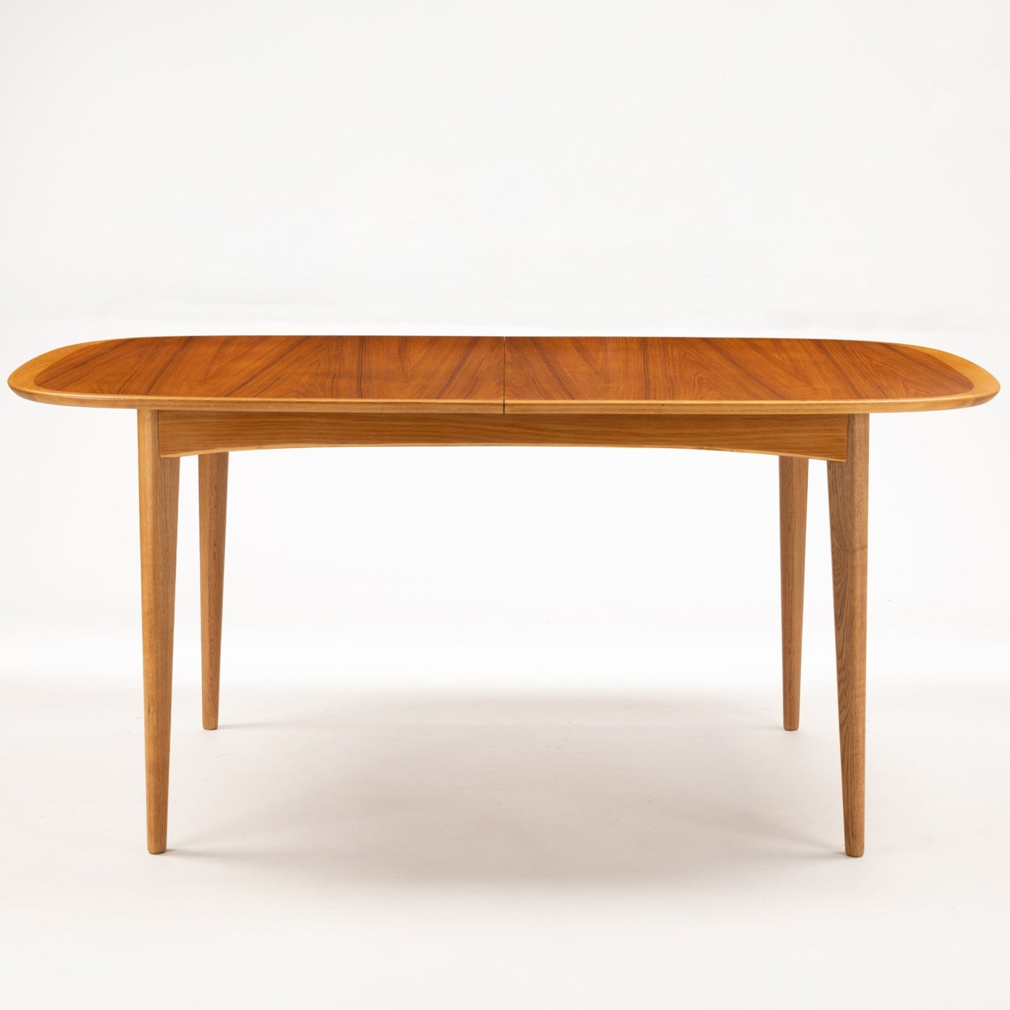 Danish Butterfly-Leaf Teak Dining Table with elongated oval top slim tapered legs and warm linear wood grain in vintage Danish furniture style