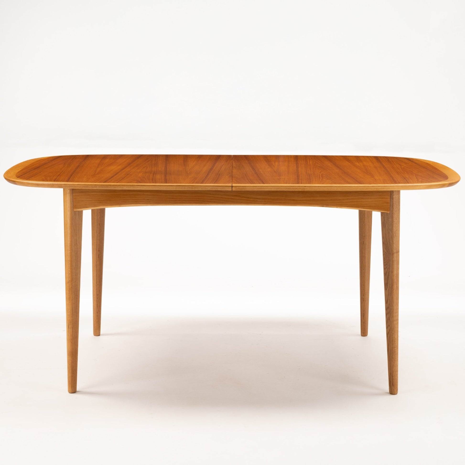 Danish Butterfly-Leaf Teak Dining Table with elongated oval top slim tapered legs and warm linear wood grain in vintage Danish furniture style
