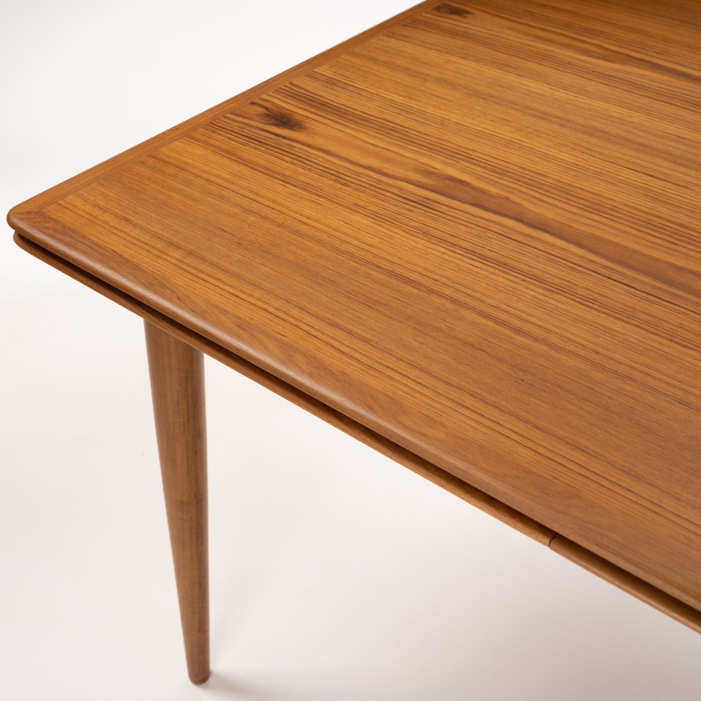 Danish Draw-Leaf Dining Table in Teak with rich wood grain rounded edges and a tapered leg showcasing vintage Danish furniture craftsmanship