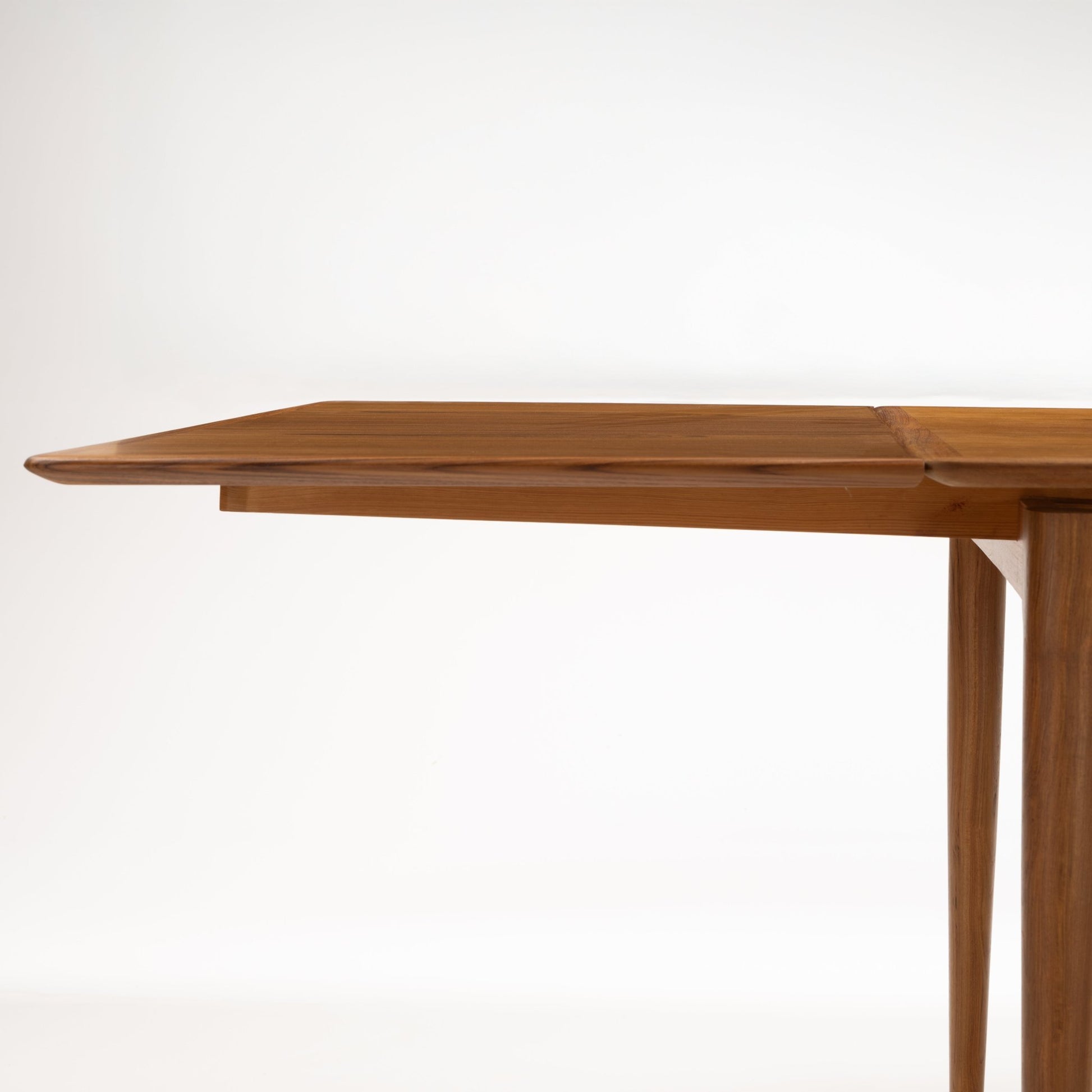 Danish Draw-Leaf Dining Table in Teak showing an extended leaf with rich linear wood grain and slender tapered legs in vintage Danish furniture style
