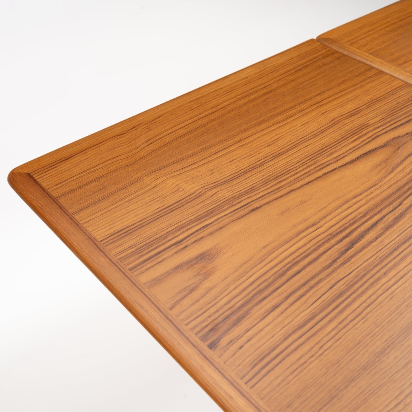 Danish Draw-Leaf Dining Table in Teak showing richly figured linear wood grain a rounded edge and framed tabletop in vintage Danish furniture style