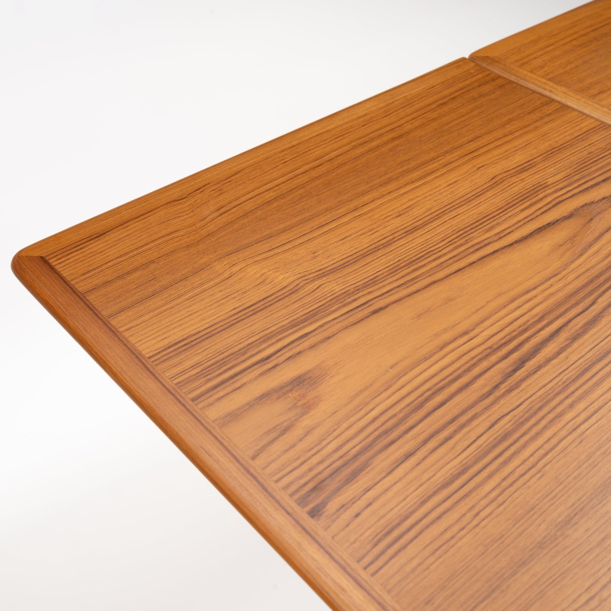 Danish Draw-Leaf Dining Table in Teak showing richly figured linear wood grain a rounded edge and framed tabletop in vintage Danish furniture style