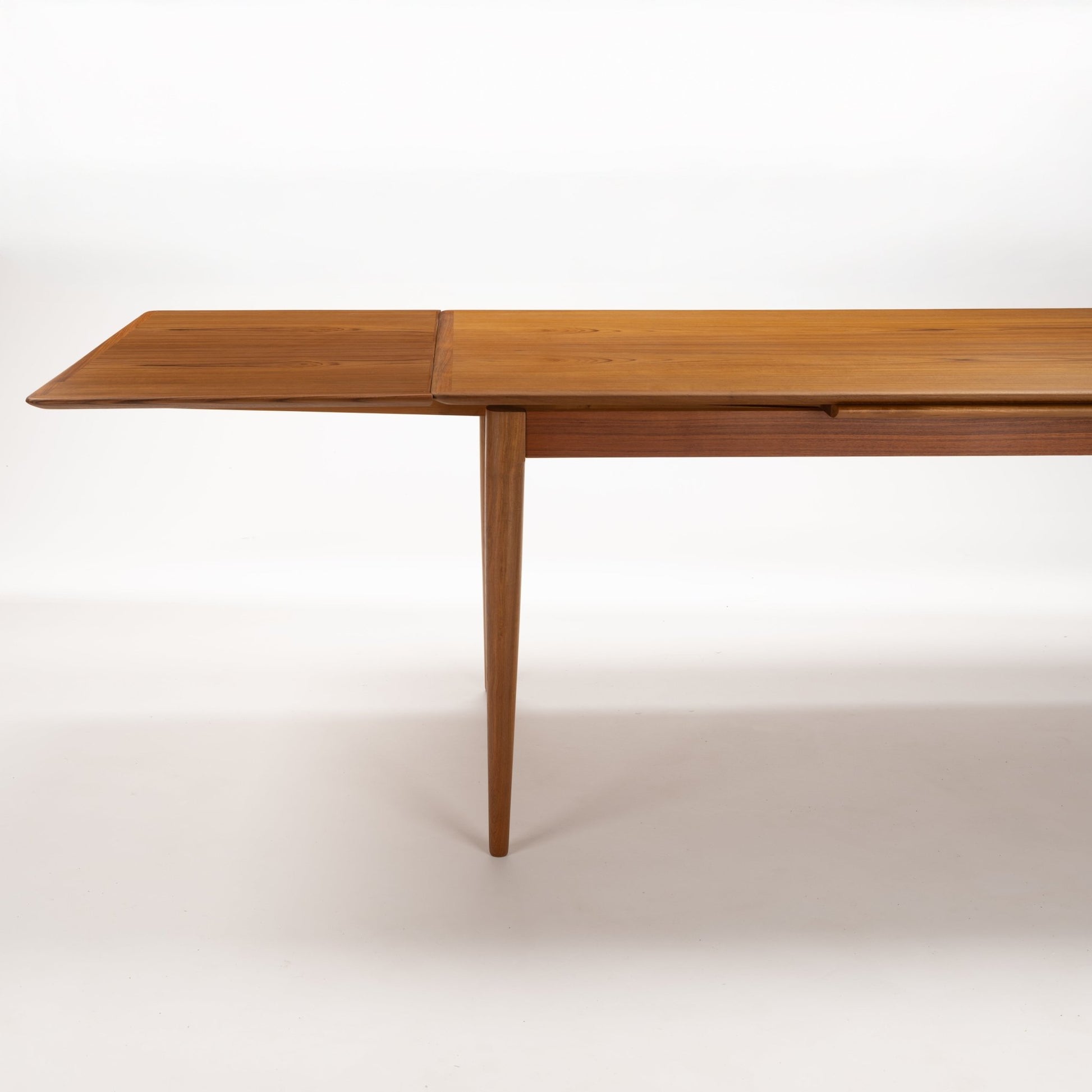 Danish Draw-Leaf Dining Table in Teak with extended tabletop leaf warm linear grain and slender tapered leg in vintage Danish furniture style