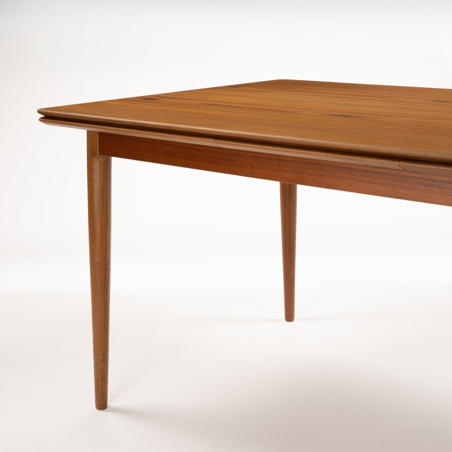 Danish Draw-Leaf Dining Table in Teak with rich wood grain rounded edges and tapered legs showcasing vintage Danish furniture craftsmanship