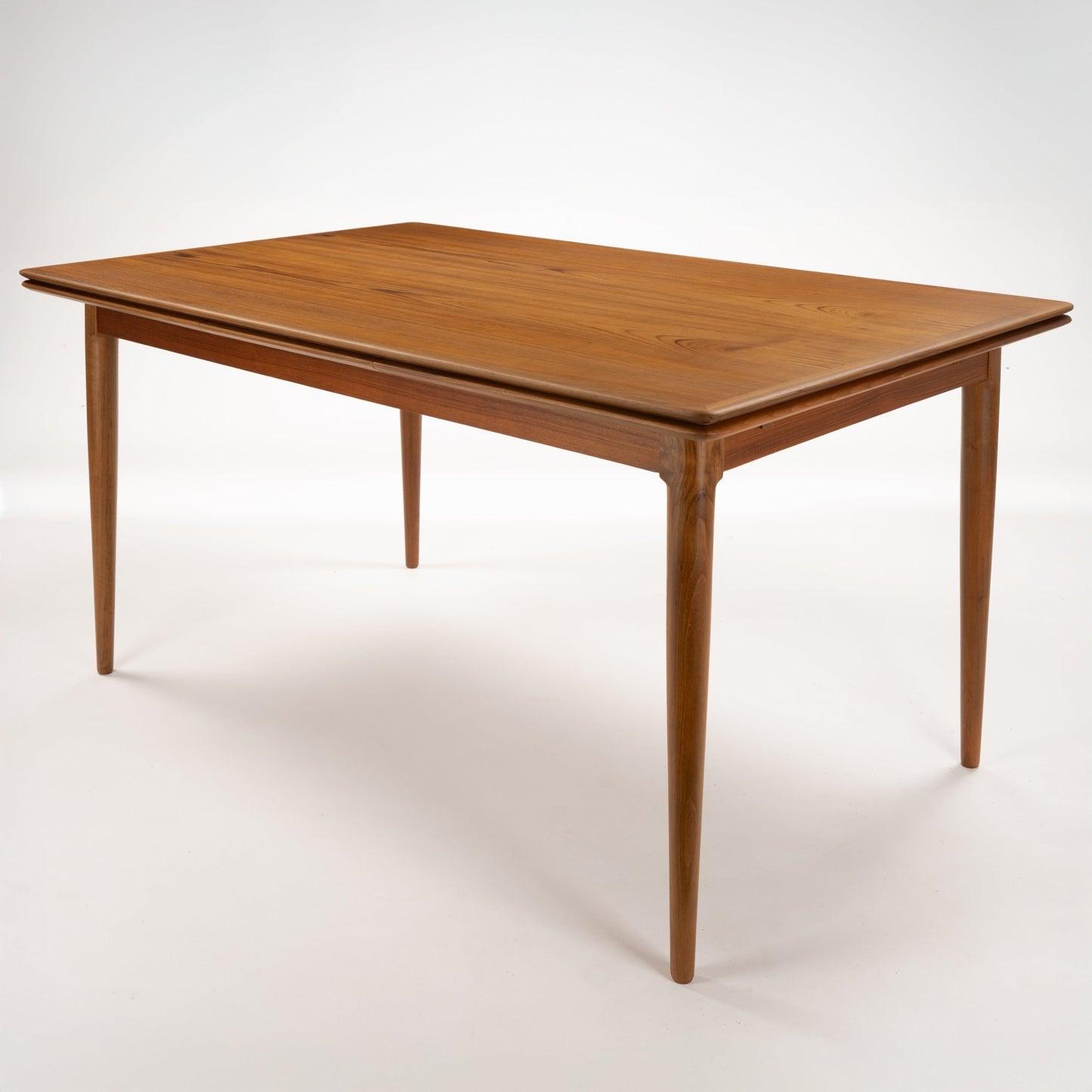 Danish Draw-Leaf Dining Table in Teak with warm natural wood grain a rounded rectangular top and tapered legs in vintage Danish furniture style