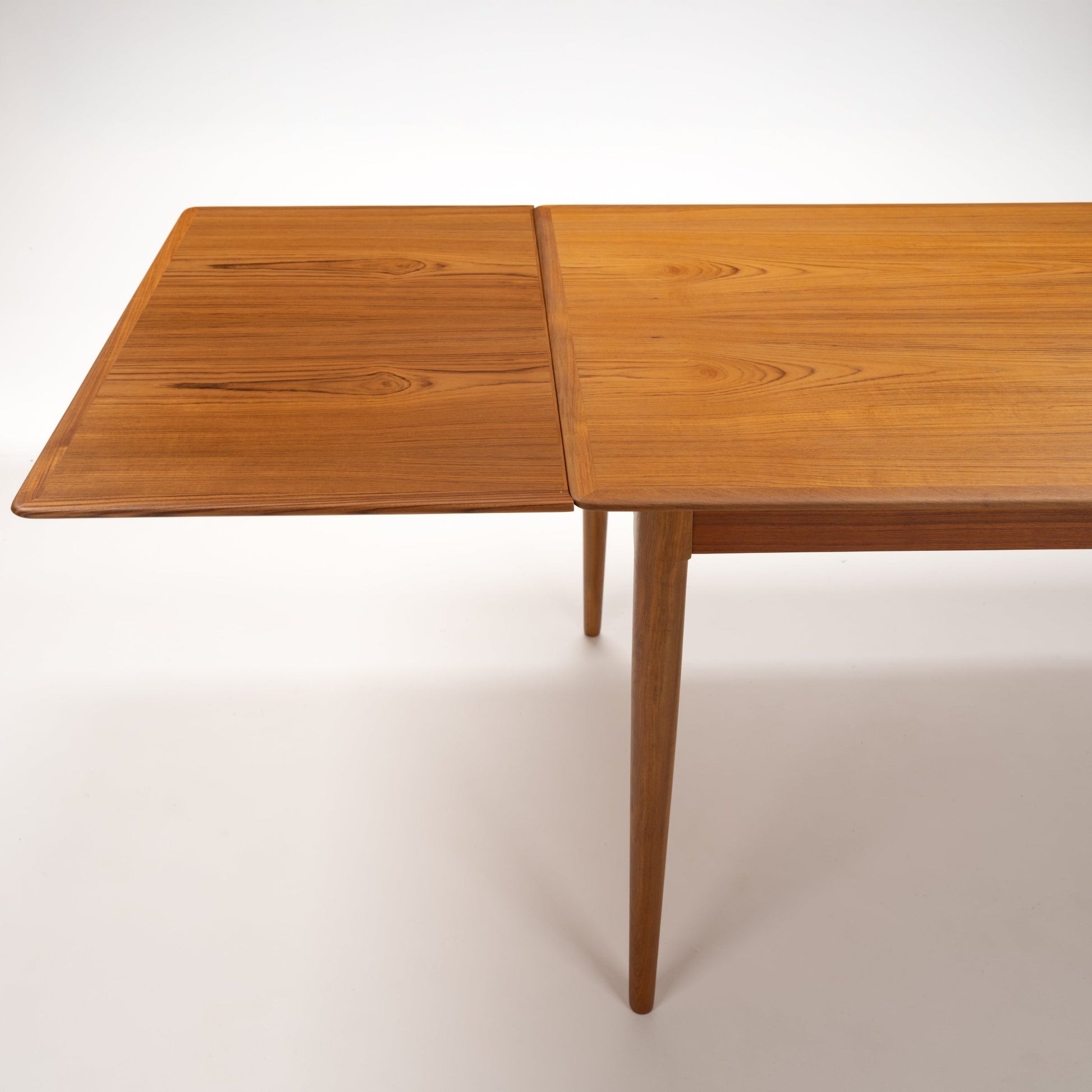 Danish Draw-Leaf Dining Table in Teak with an extended leaf warm wood grain and tapered legs in vintage Danish furniture style