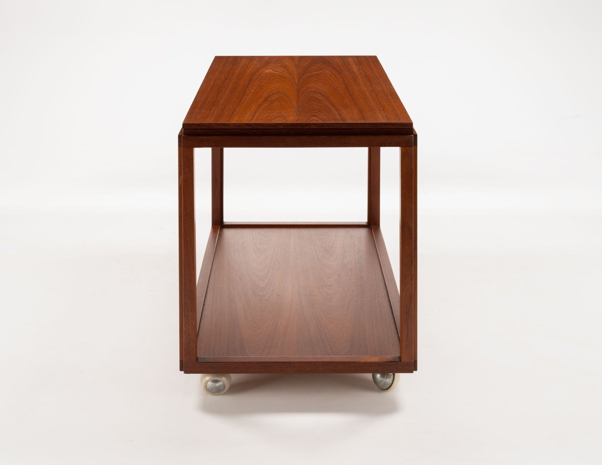 Danish teak expanding bar cart with minimalist design and wheels for mobility, showing front view of closed top surface