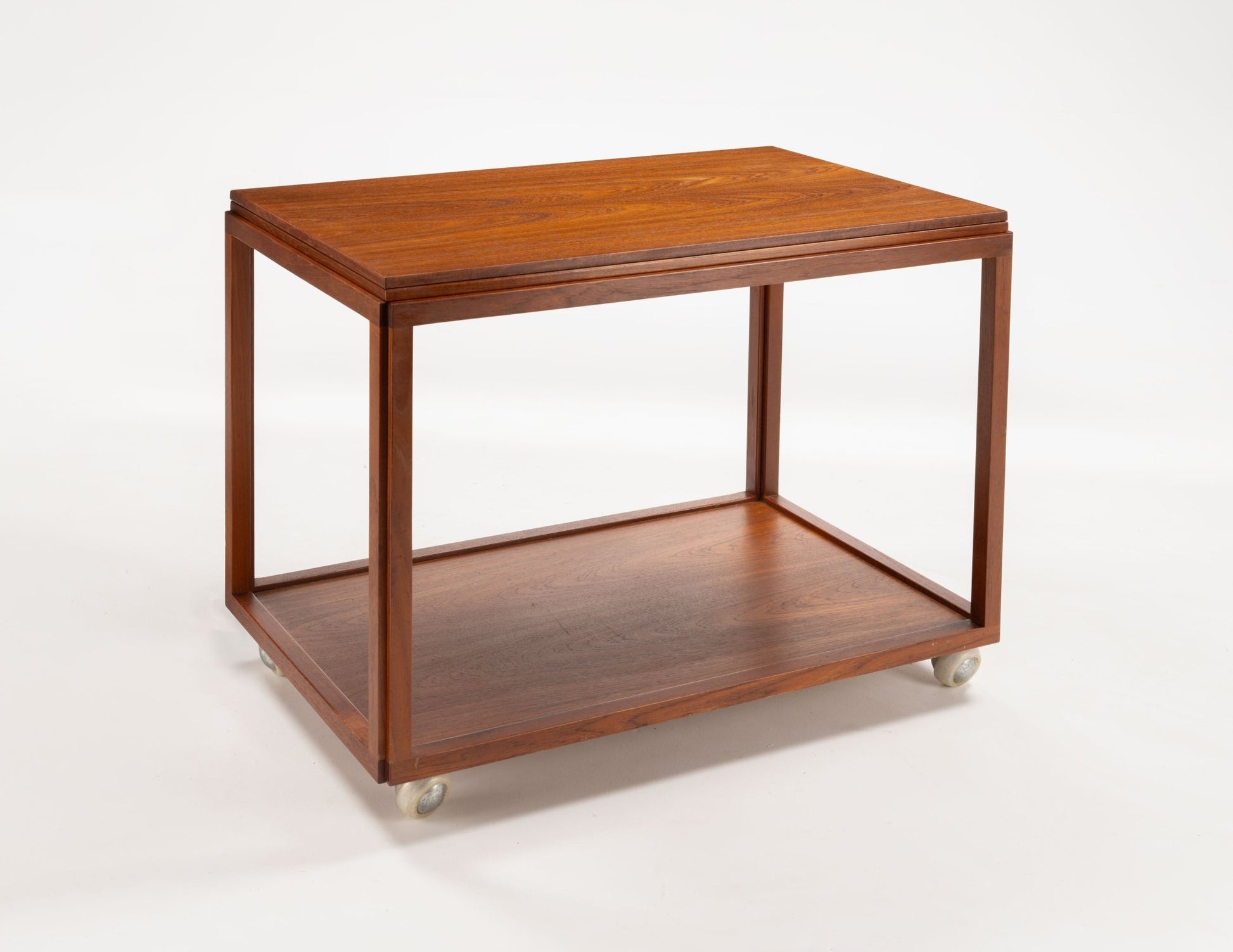 Danish teak expanding bar cart with clean lines and casters, showing compact closed form on white background.