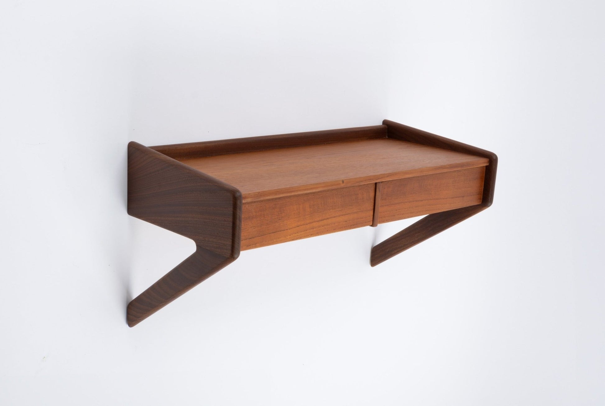 Danish modern teak wall-mounted shelf with two drawers and sculptural angled supports on white background