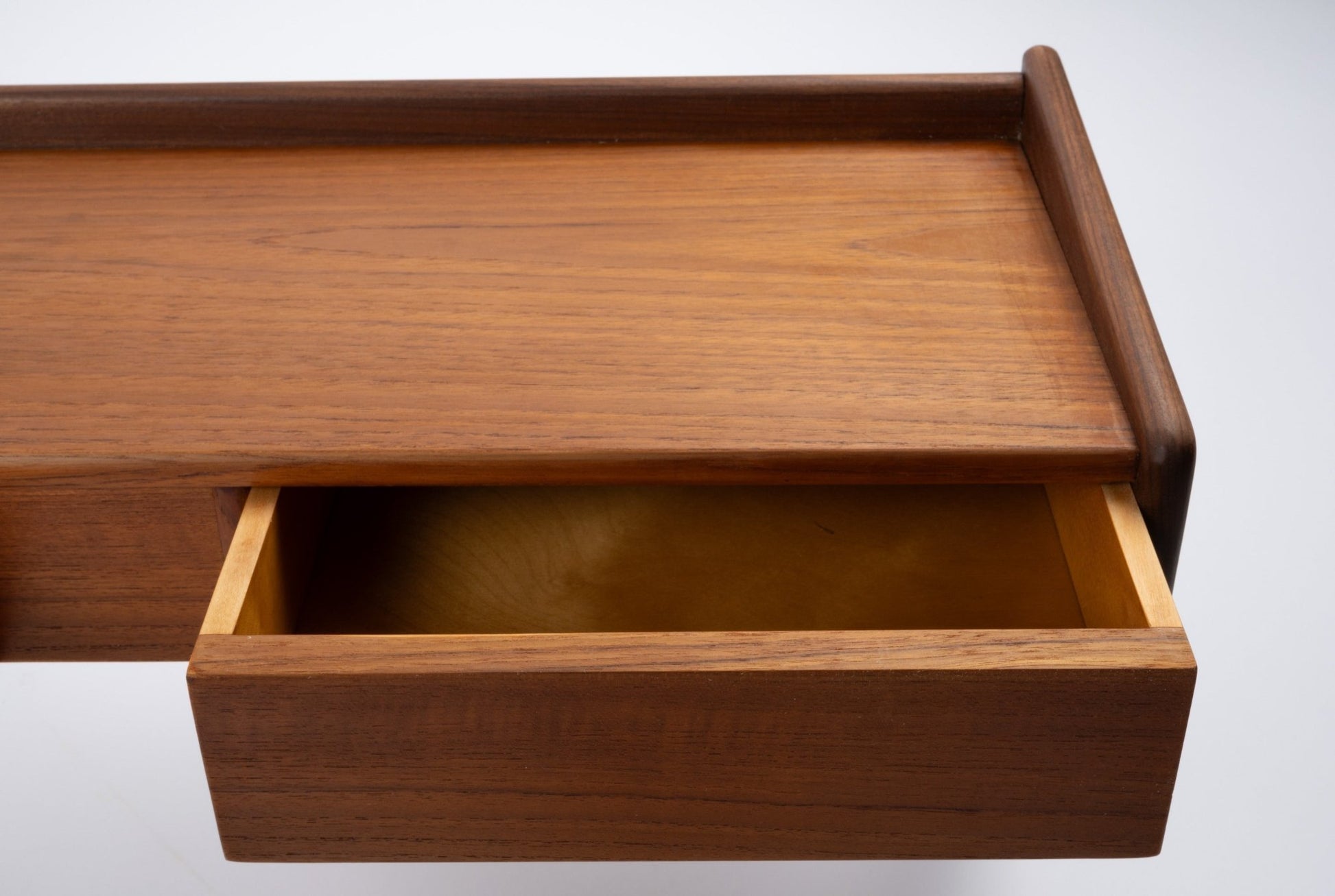 Danish modern teak shelf with open drawer, featuring clean lines and warm wood finish on white background.