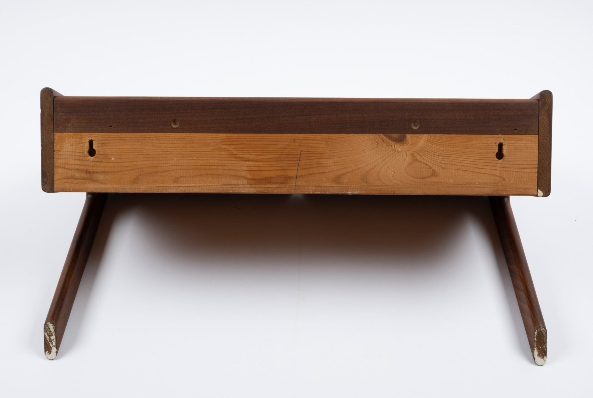 Danish modern teak shelf with drawer, wall-mount hooks, and angled legs, shown from bottom view on white background.