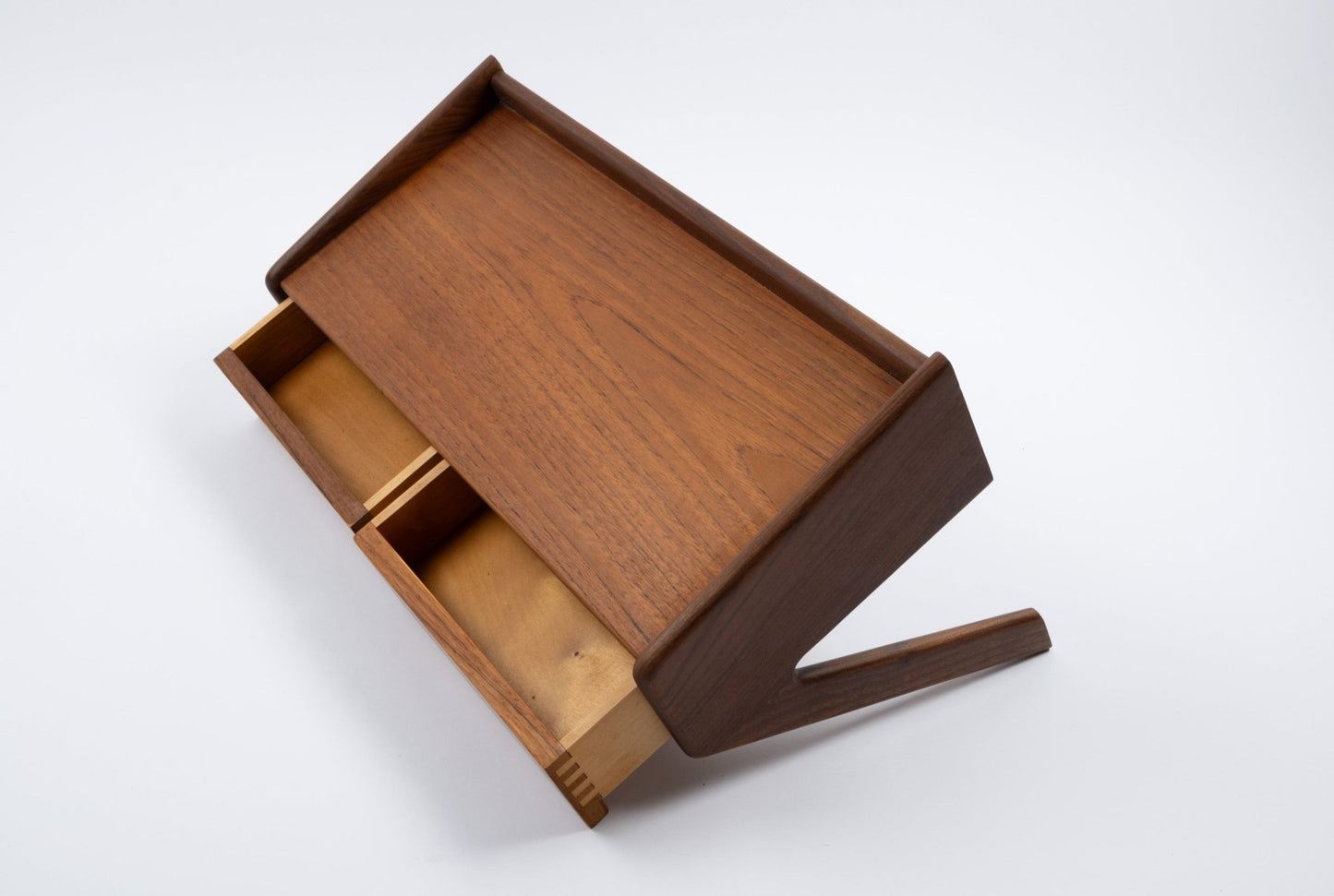 Danish modern teak shelf with angled sides and single open drawer showing interior compartments on white background
