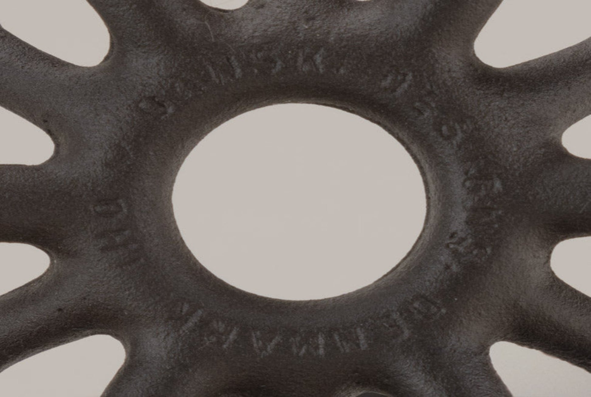 Close-up of black Dansk cast iron spider candleholder with Jens Quistgaard Denmark maker's mark on textured surface