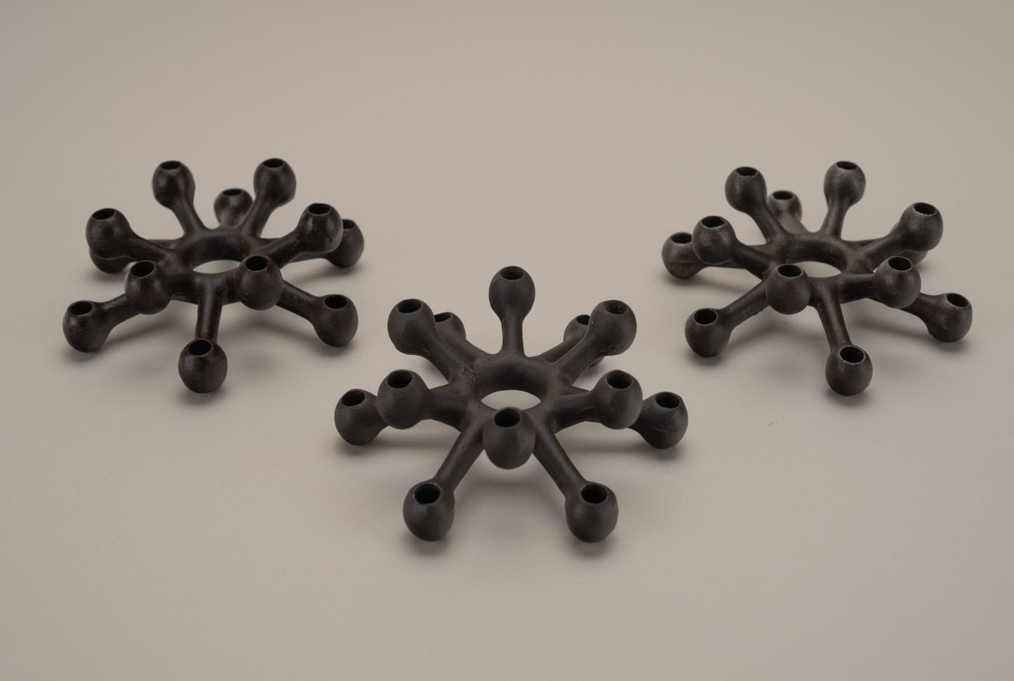 Set of three Dansk Jens Quistgaard cast iron spider candleholders with multiple arms for thin candles, mid-century design.