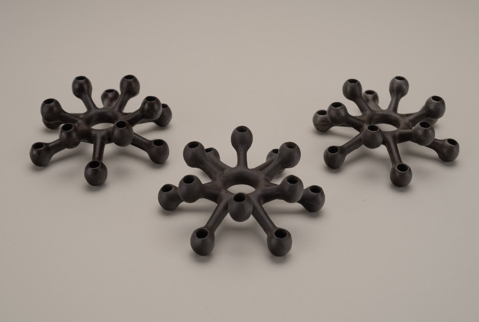 Set of three Dansk Jens Quistgaard cast iron spider candleholders with multiple arms for thin candles, mid-century design.