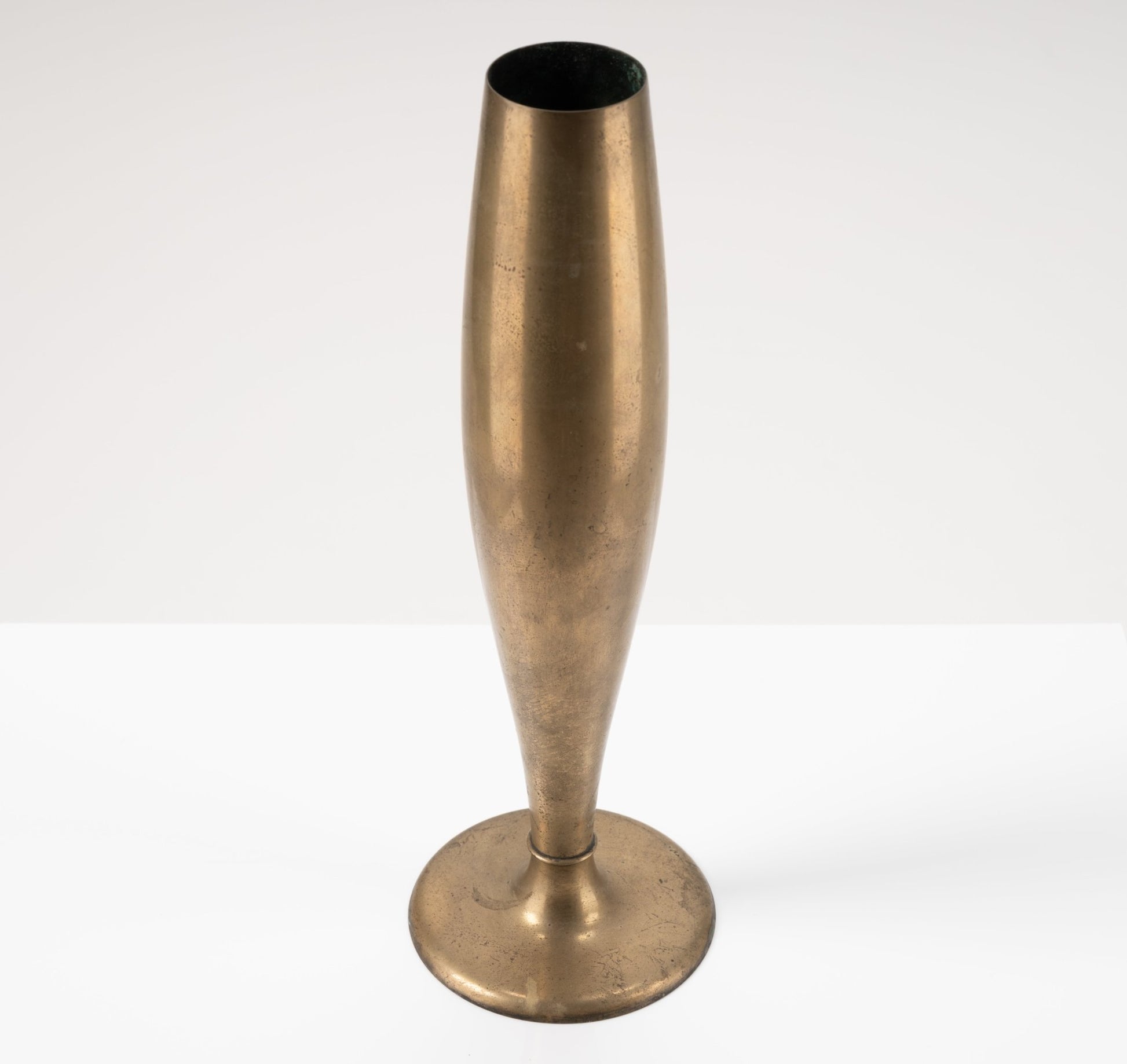 Dirigold metal bud vase with warm brass patina and 3.75-inch wide stable base, Swedish 1930s design on white background