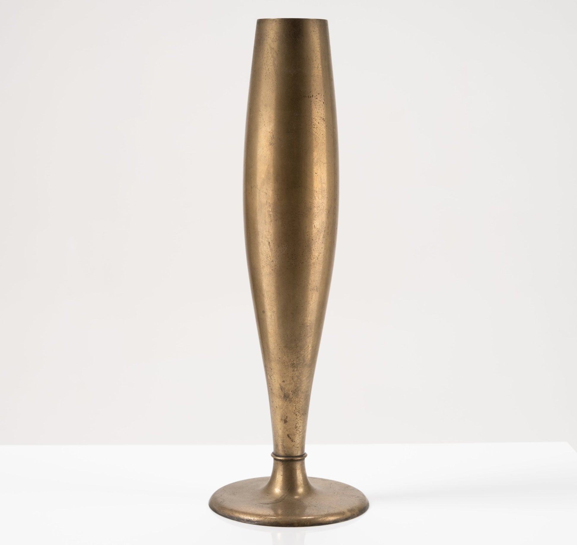 Tall Dirigold metal bud vase with warm brass patina and stable round base, Swedish design from the 1930s on white background