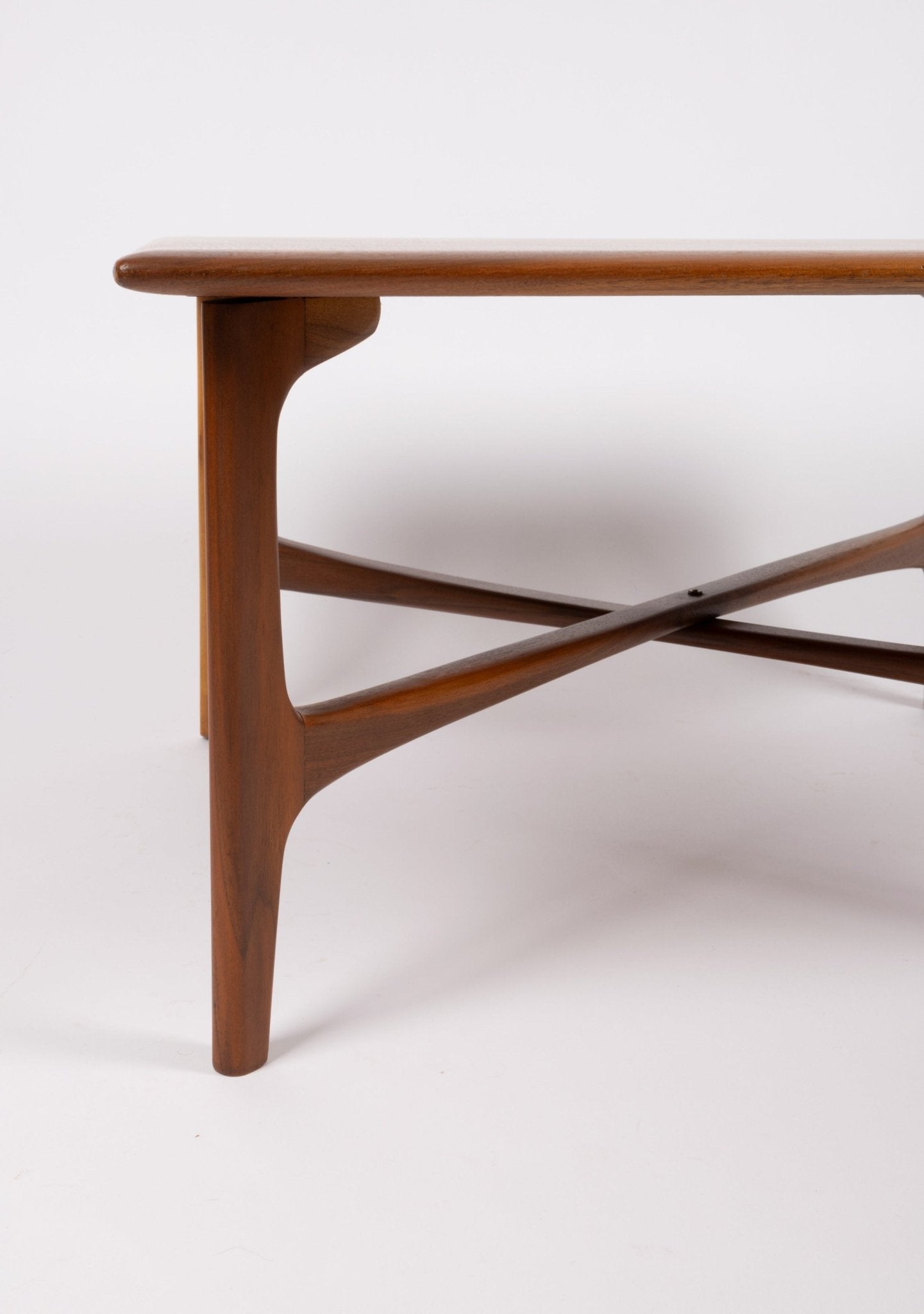 Close-up of mid-century modern DUX coffee table corner showing teak wood x-base and framed edge design