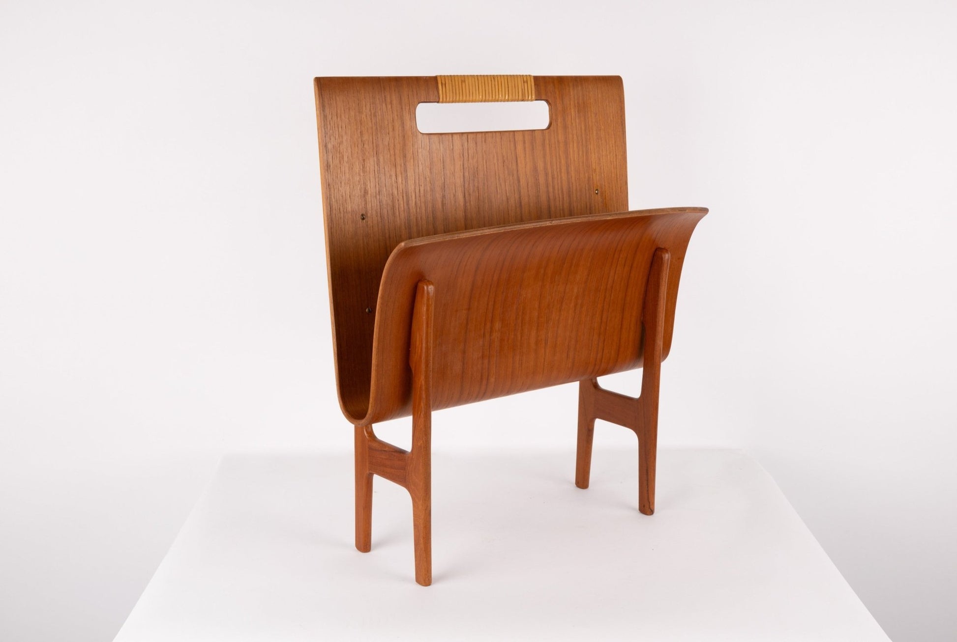 Ejner Larsen mid-century modern teak magazine rack with sculpted frame and original cane handle on white background