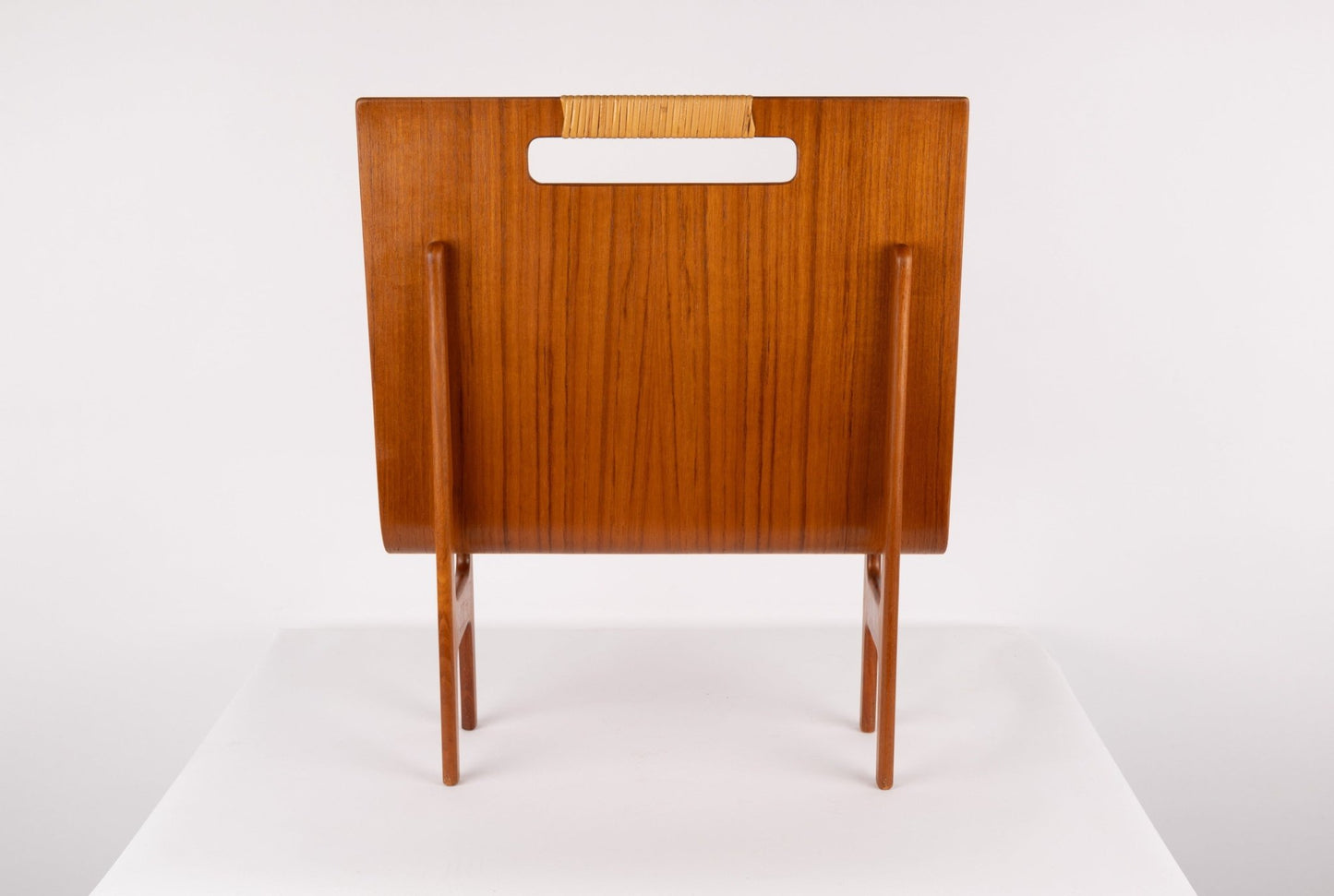 1960s Danish teak magazine rack with sculpted frame and original cane handle on white background