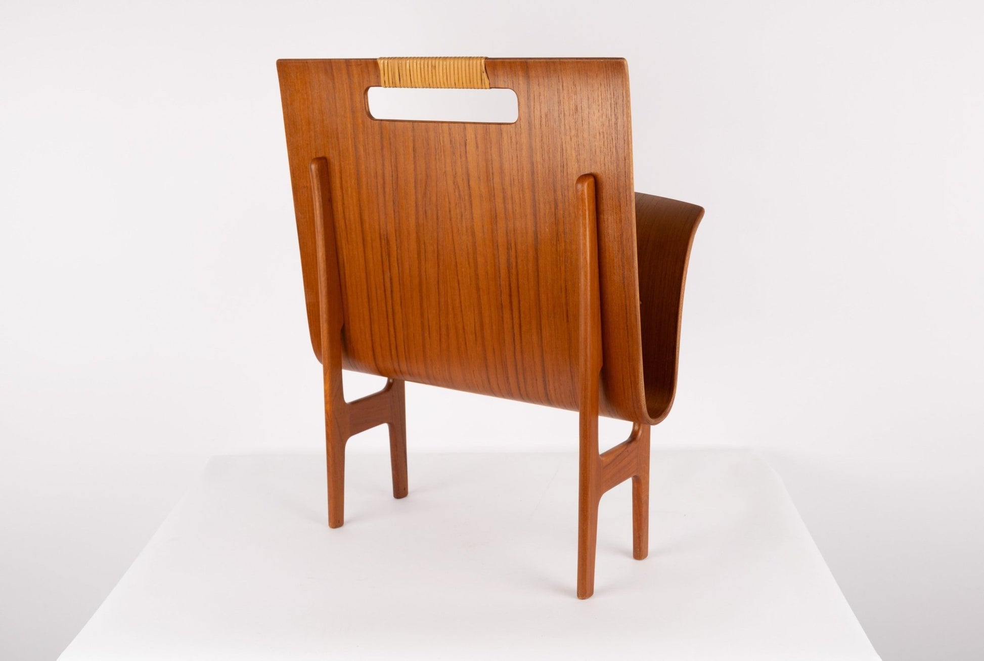 1960s mid-century modern Ejner Larsen teak magazine rack with sculpted frame and original cane handle on white background