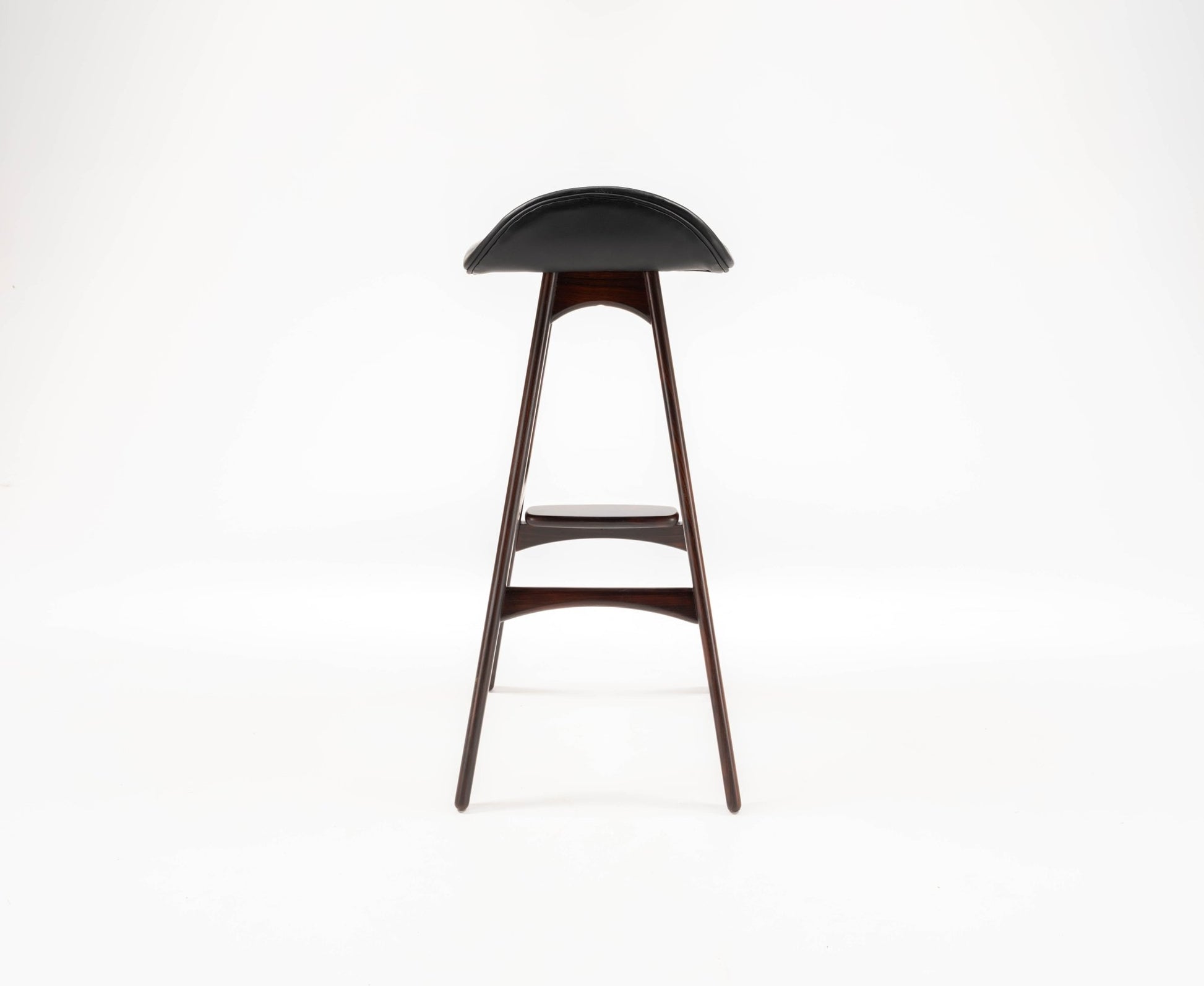 Mid-century modern Erik Buch rosewood bar stool with curved black leather seat and slender tapered legs on white background