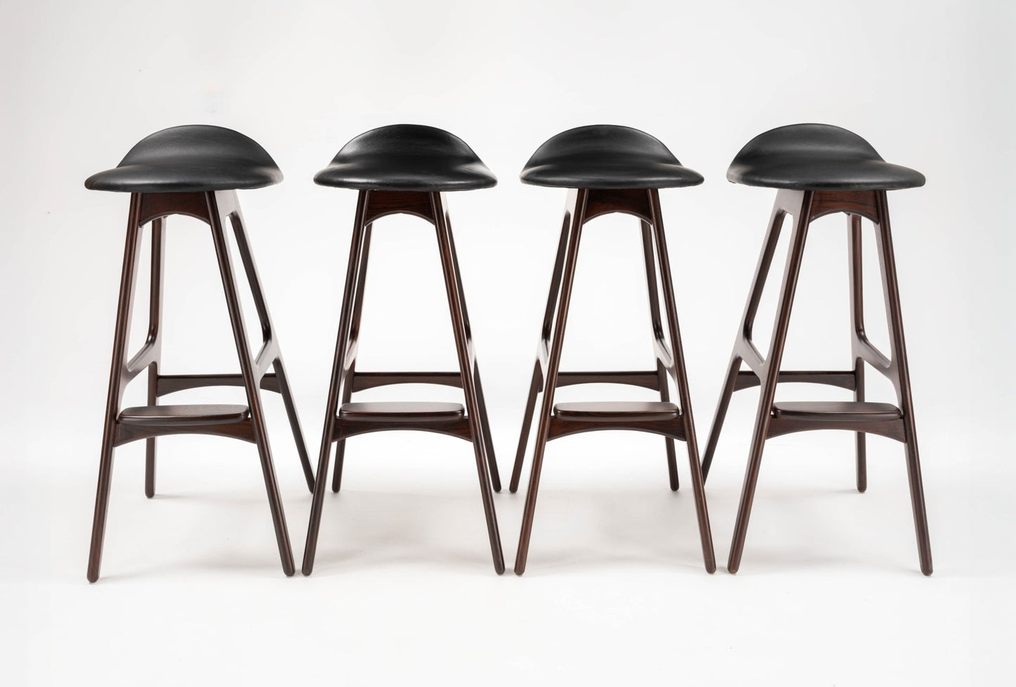 Set of four mid-century modern Erik Buch rosewood bar stools with black leather contoured seats and angled legs