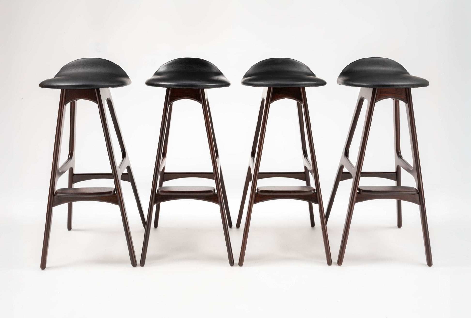 Set of four mid-century modern Erik Buch rosewood bar stools with black leather contoured seats and angled legs