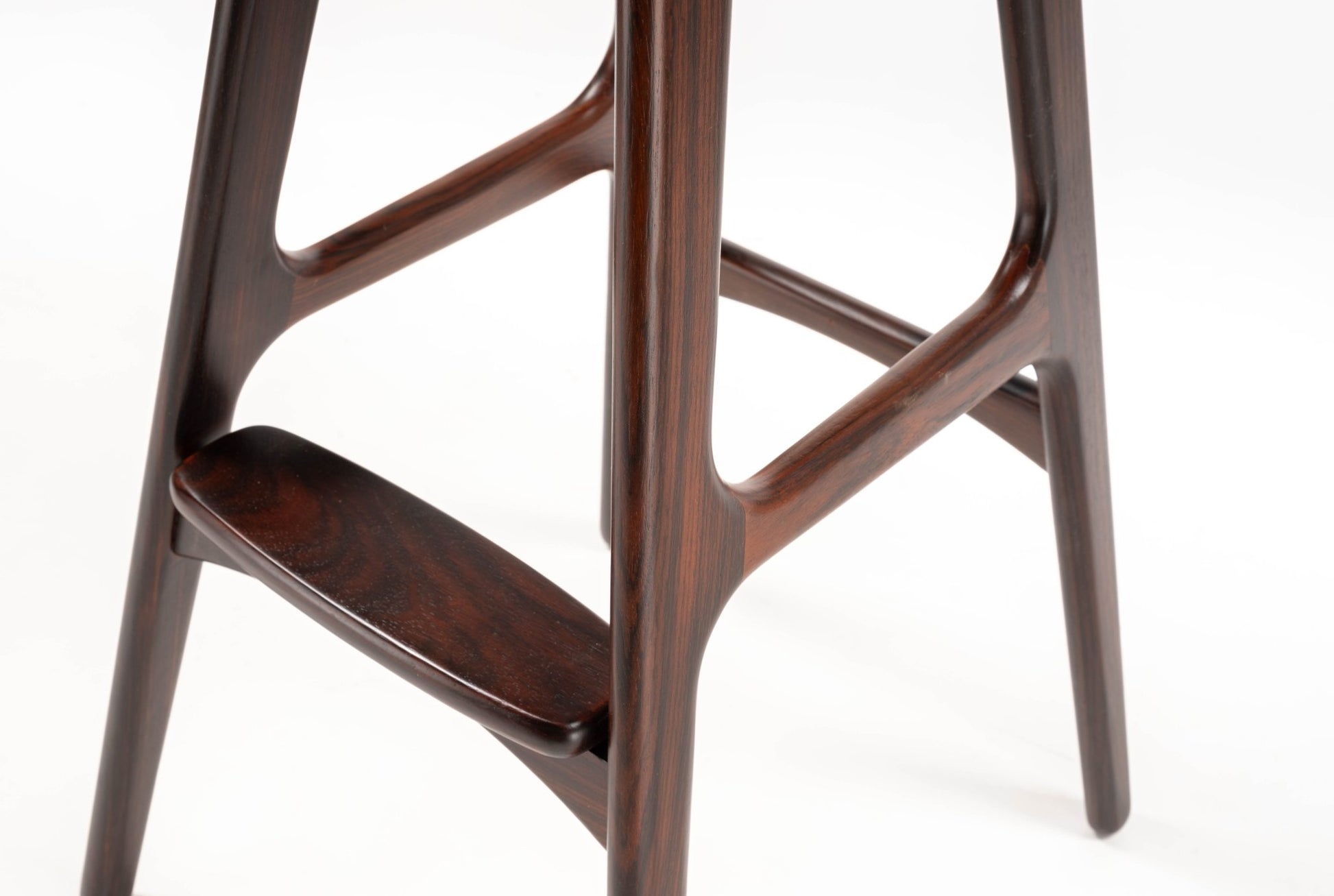 Close-up of mid-century modern Erik Buch rosewood stool leg and footrest with smooth, sculpted grain finish