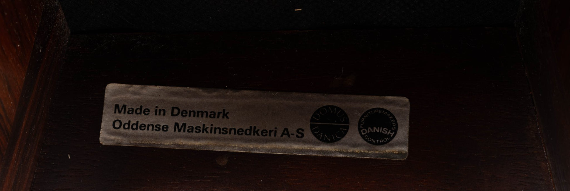 Close-up of metal label on Erik Buch rosewood stool, marked Made in Denmark by Oddense Maskinsnedkeri A-S