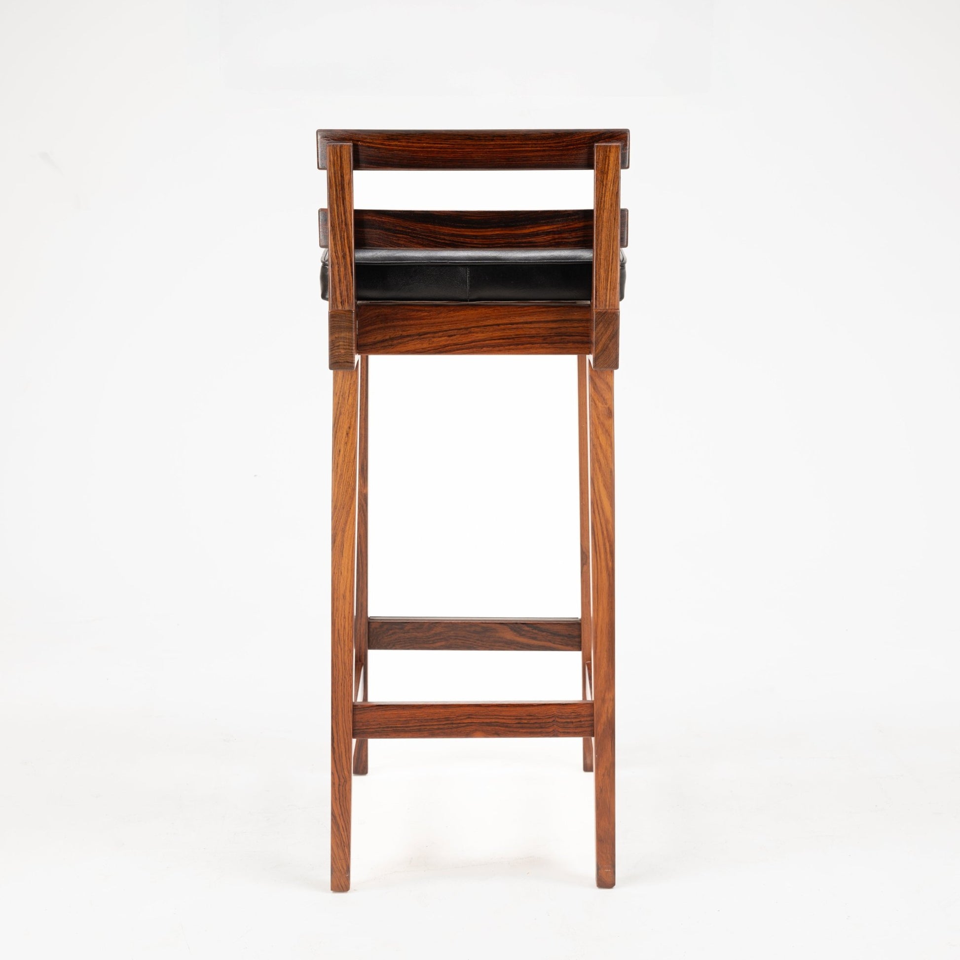 Erik Buck Pair of Rosewood Stools viewed from the back, highlighting rich rosewood grain with clean lines, horizontal backrest slats, and a black leather cushioned seat reflecting mid century modern seating design.