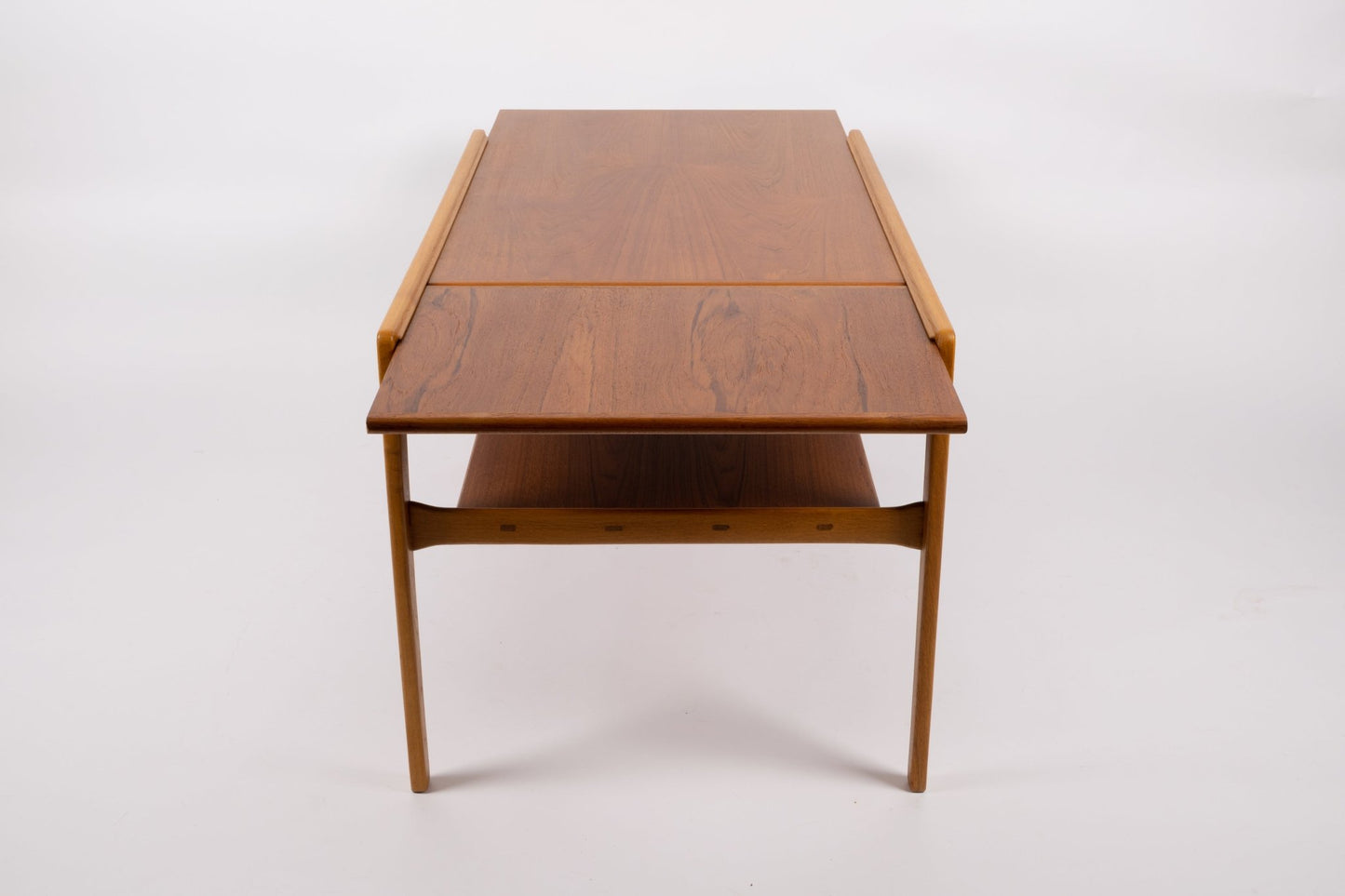 Mid-century modern expandable coffee table with pivoting teak top and tapered legs on white background