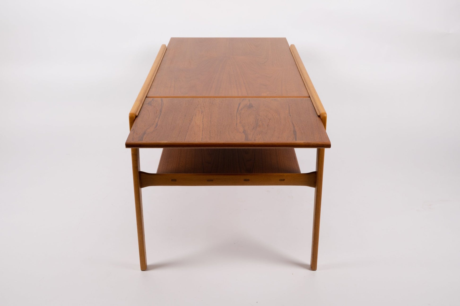Mid-century modern expandable coffee table with pivoting teak top and tapered legs on white background