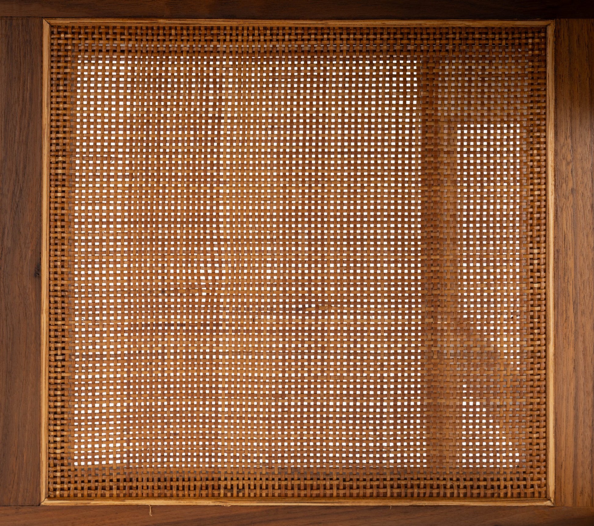 Close-up of mid-century modern walnut desk panel with woven cane detailing from the 1950s Finn Juhl design.