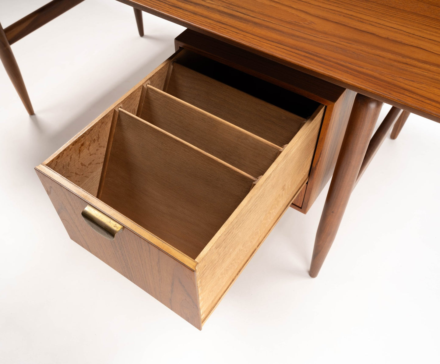 Mid-century modern walnut executive desk drawer with compartments and brass handle, showcasing fine woodworking details.
