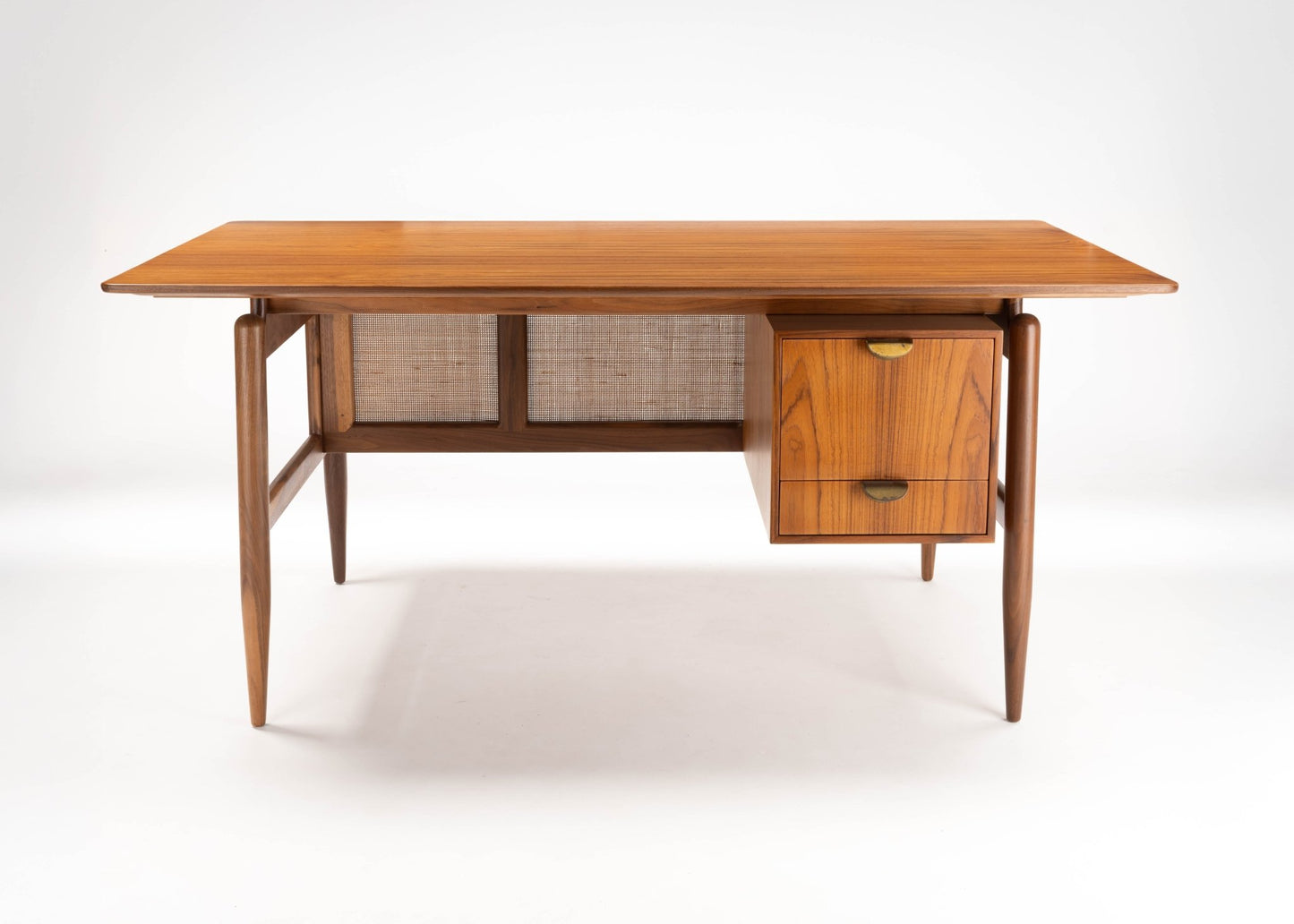 Mid-century modern walnut executive desk with cane paneling, tapered legs, and two drawers on right side.