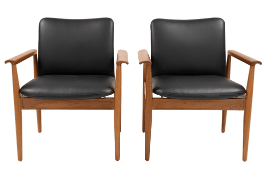 Pair of Finn Juhl Model 209 “Diplomat” chairs with teak frames and black leather cushions on tapered legs