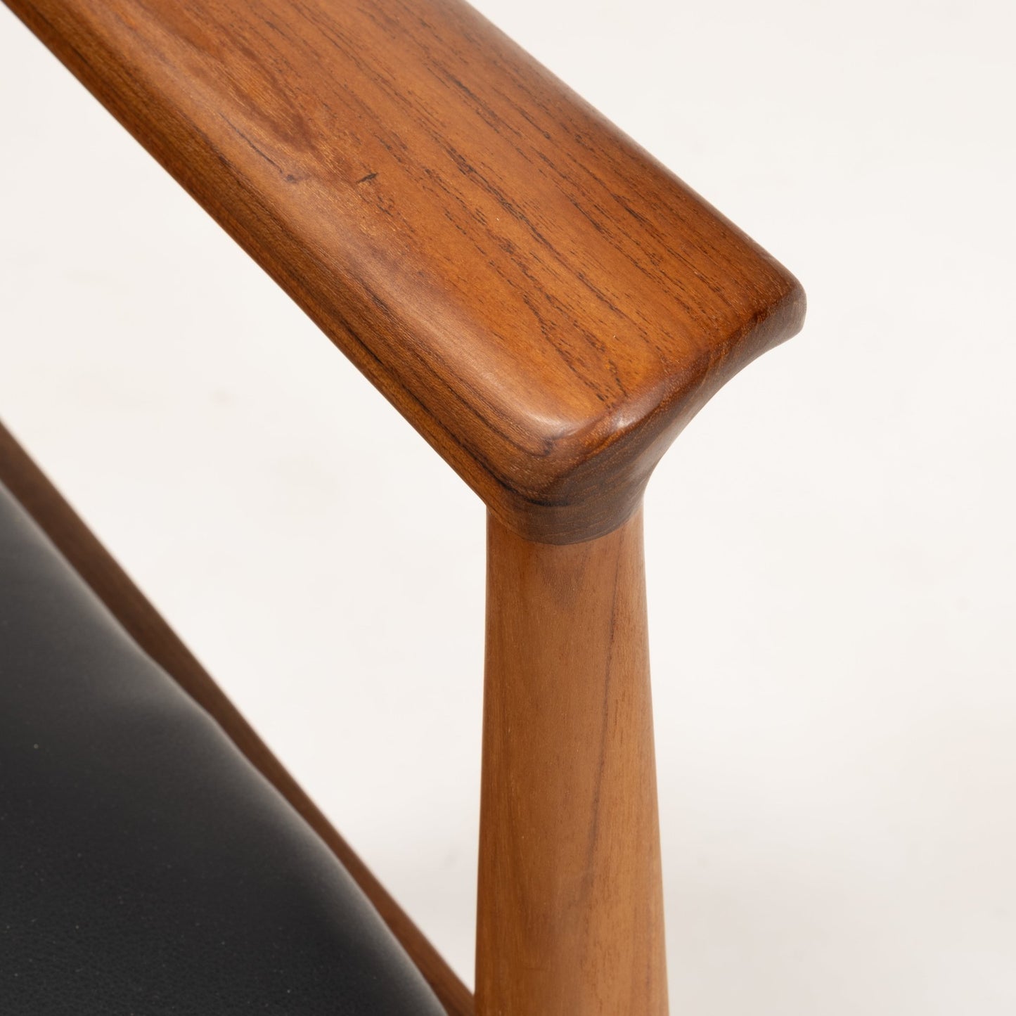 Close-up of hand-finished teak armrest and black leather seat of Finn Juhl Model 209 "Diplomat" chair