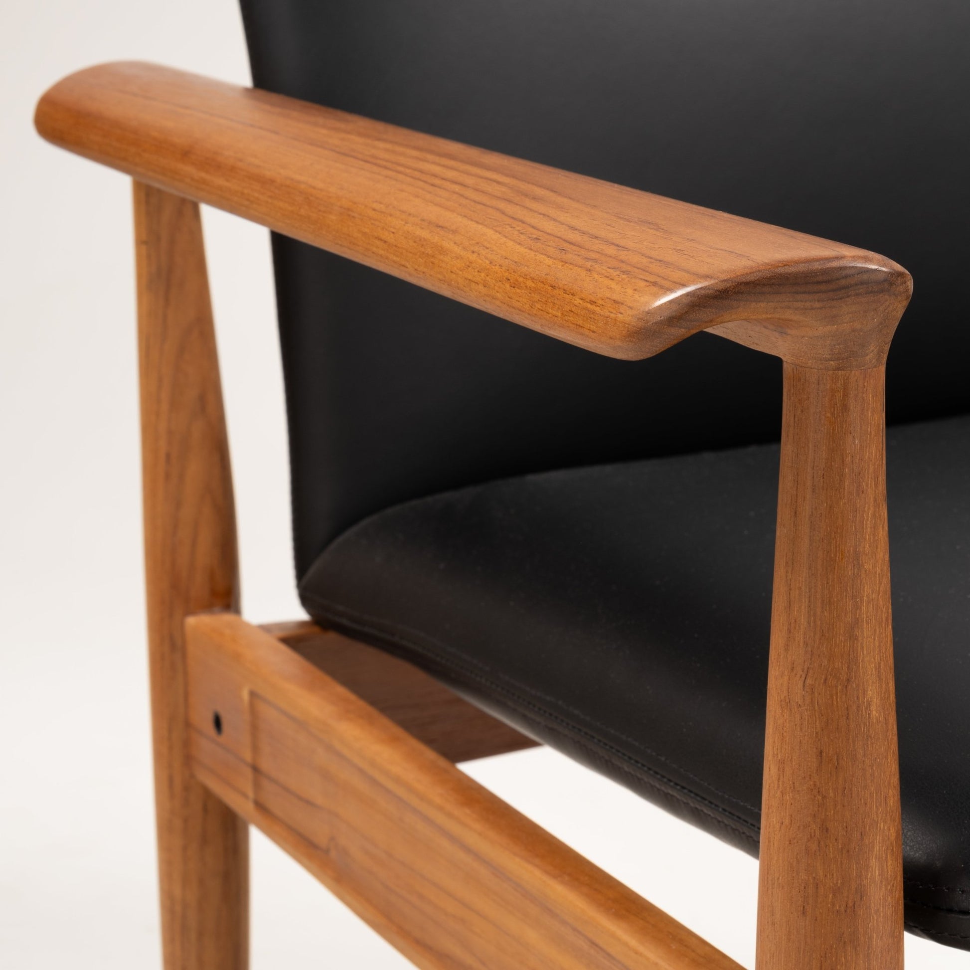 Close-up of hand-polished teak armrest and black leather cushion on Finn Juhl Model 209 "Diplomat" chair
