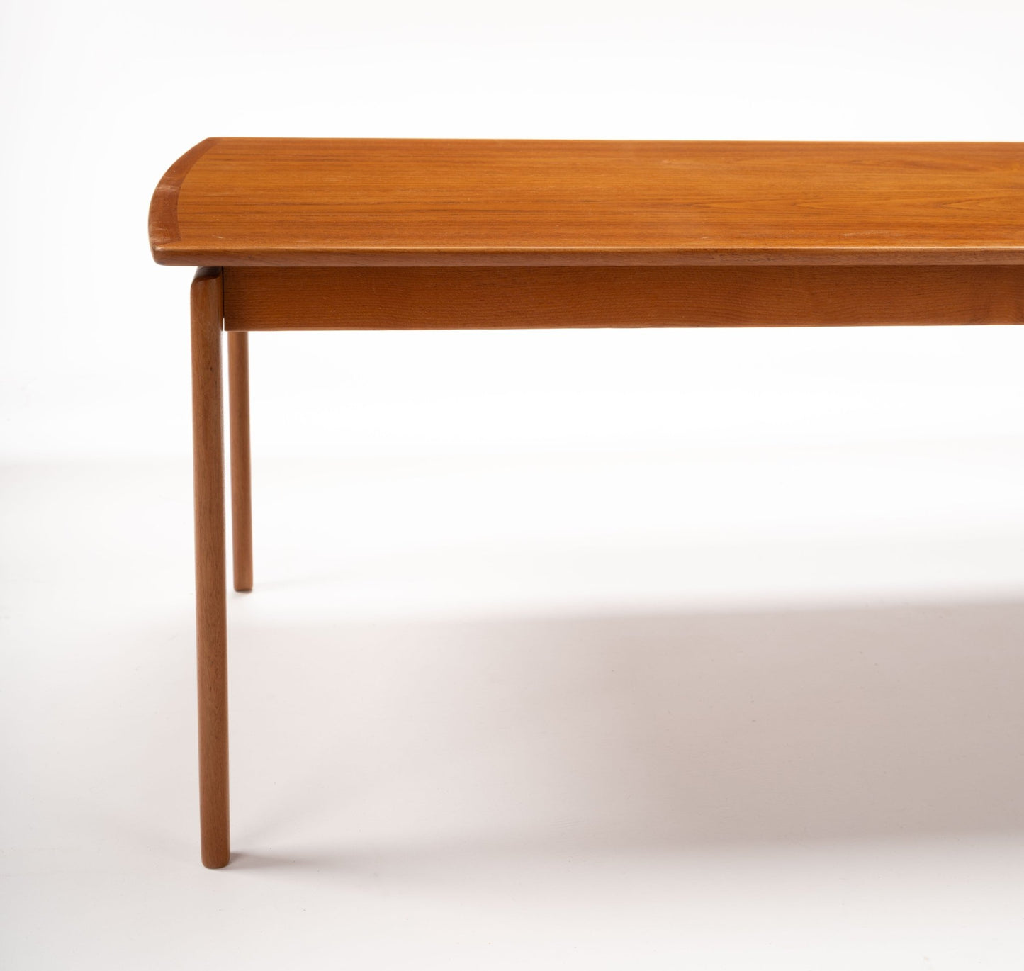 Mid-century modern teak coffee table with floating top design and slender tapered legs on white background