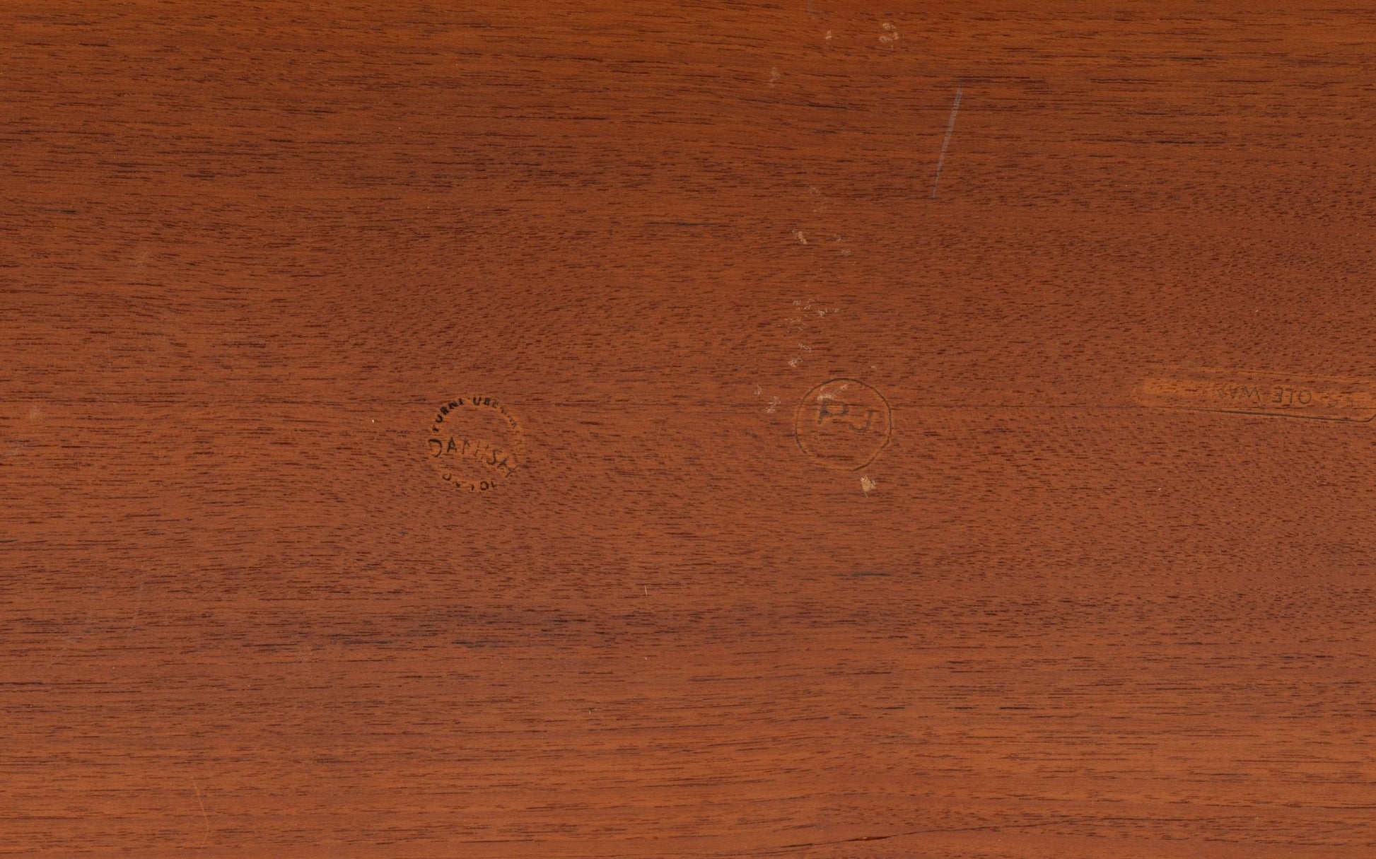 Close-up of teak wood surface with natural grain and circular imprints on mid-century modern furniture piece