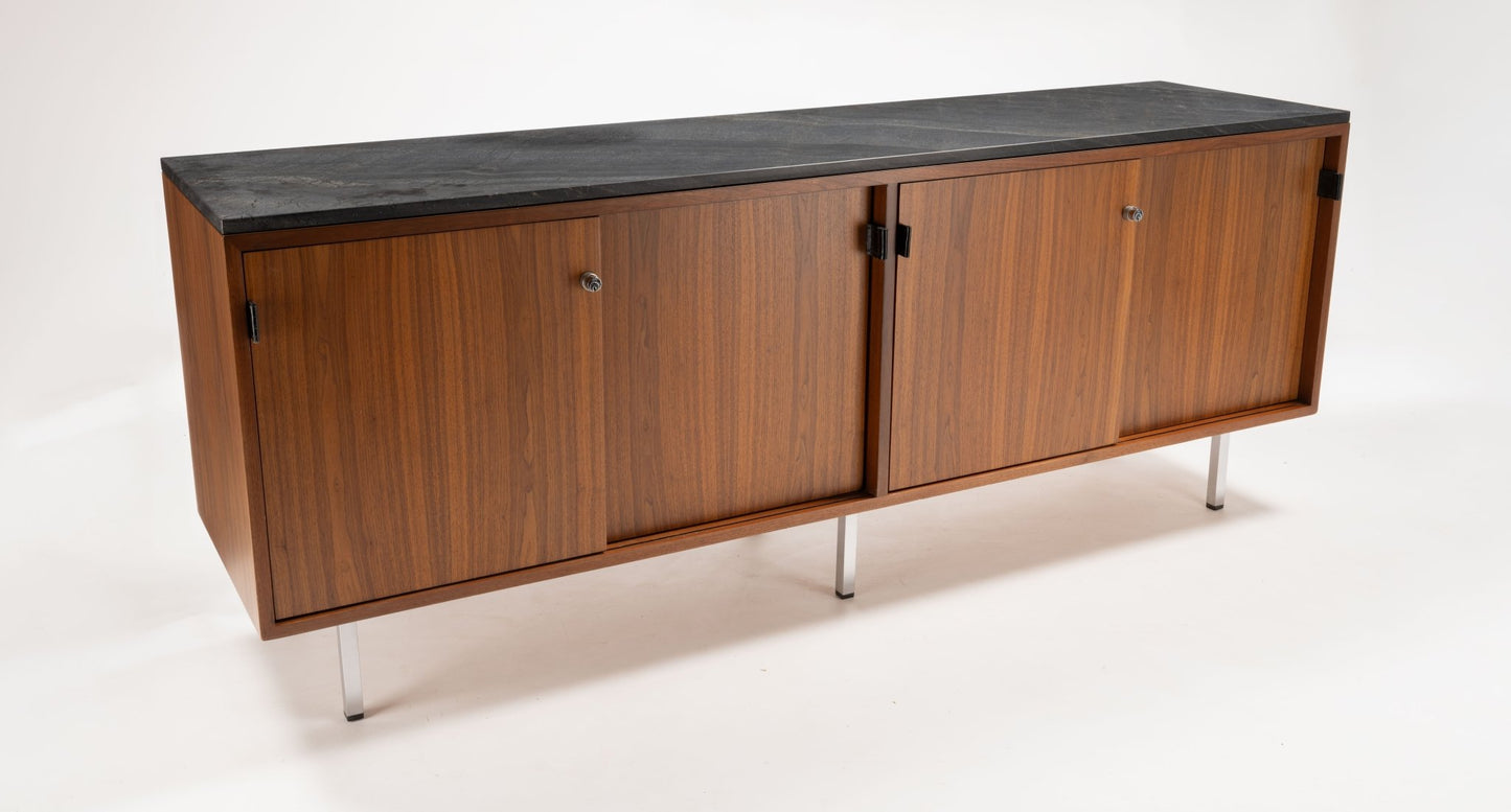 Mid-century walnut credenza with four locking sliding doors, leather pulls, and black marble top on polished metal legs.