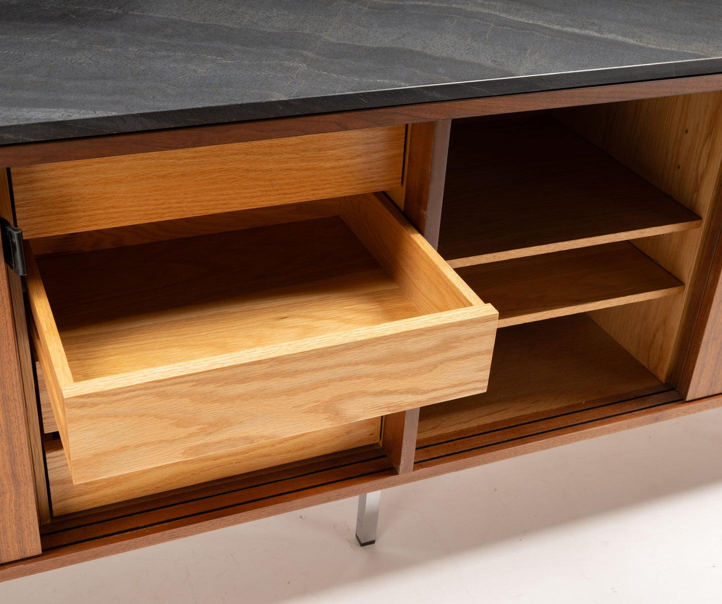 Florence Knoll credenza with black marble top, open shelving, and sliding door with leather pull showing drawer interior