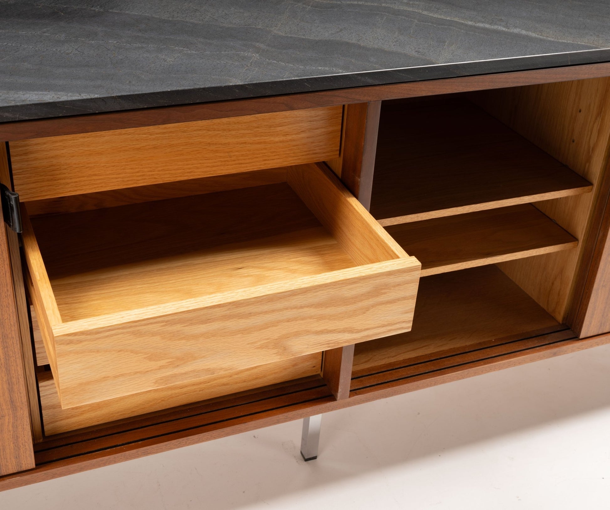 Florence Knoll credenza with black marble top, open shelving, and sliding door with leather pull showing drawer interior