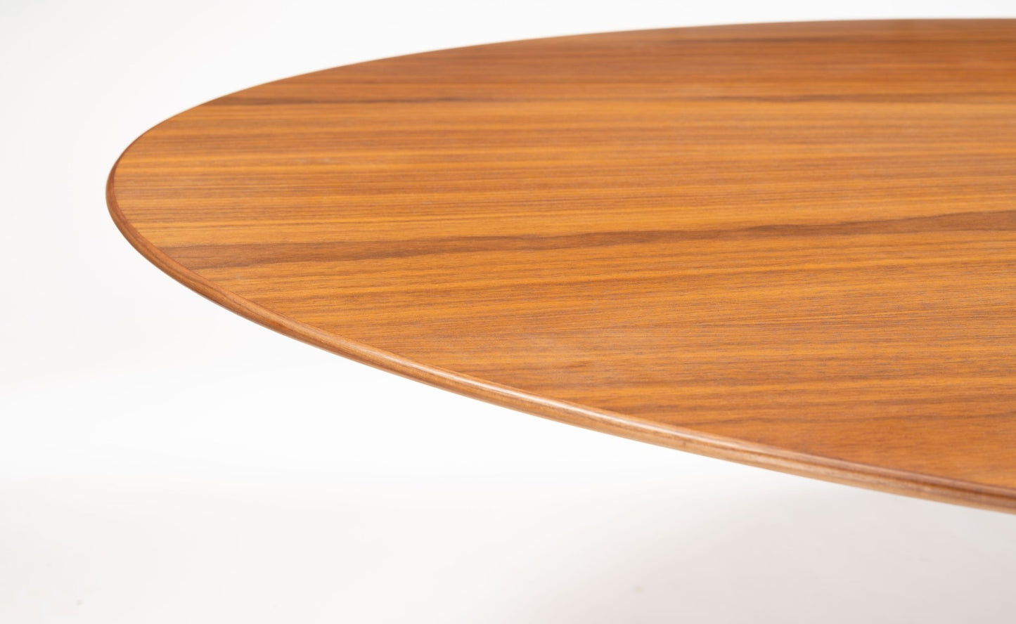 Close-up of mid-century modern oval dining table with finely grained walnut top and smooth rounded edges