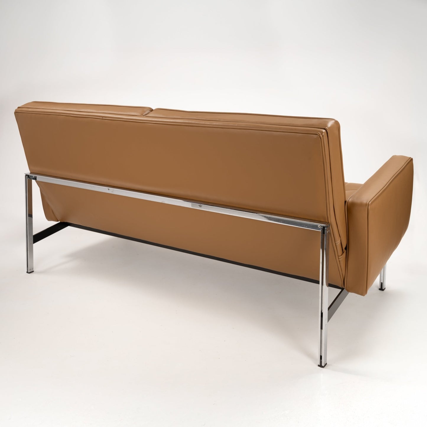 Florence Knoll 'Relaxed' Settee in Leather viewed from the rear with caramel brown upholstery chrome frame and slender legs in mid century modern furniture style