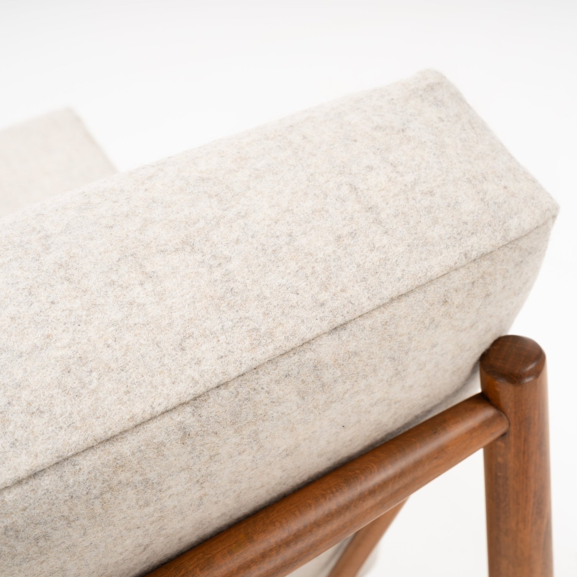 Close-up of beige wool cushion on Folke Ohlsson slipper chair showing warm-toned beechwood frame detail