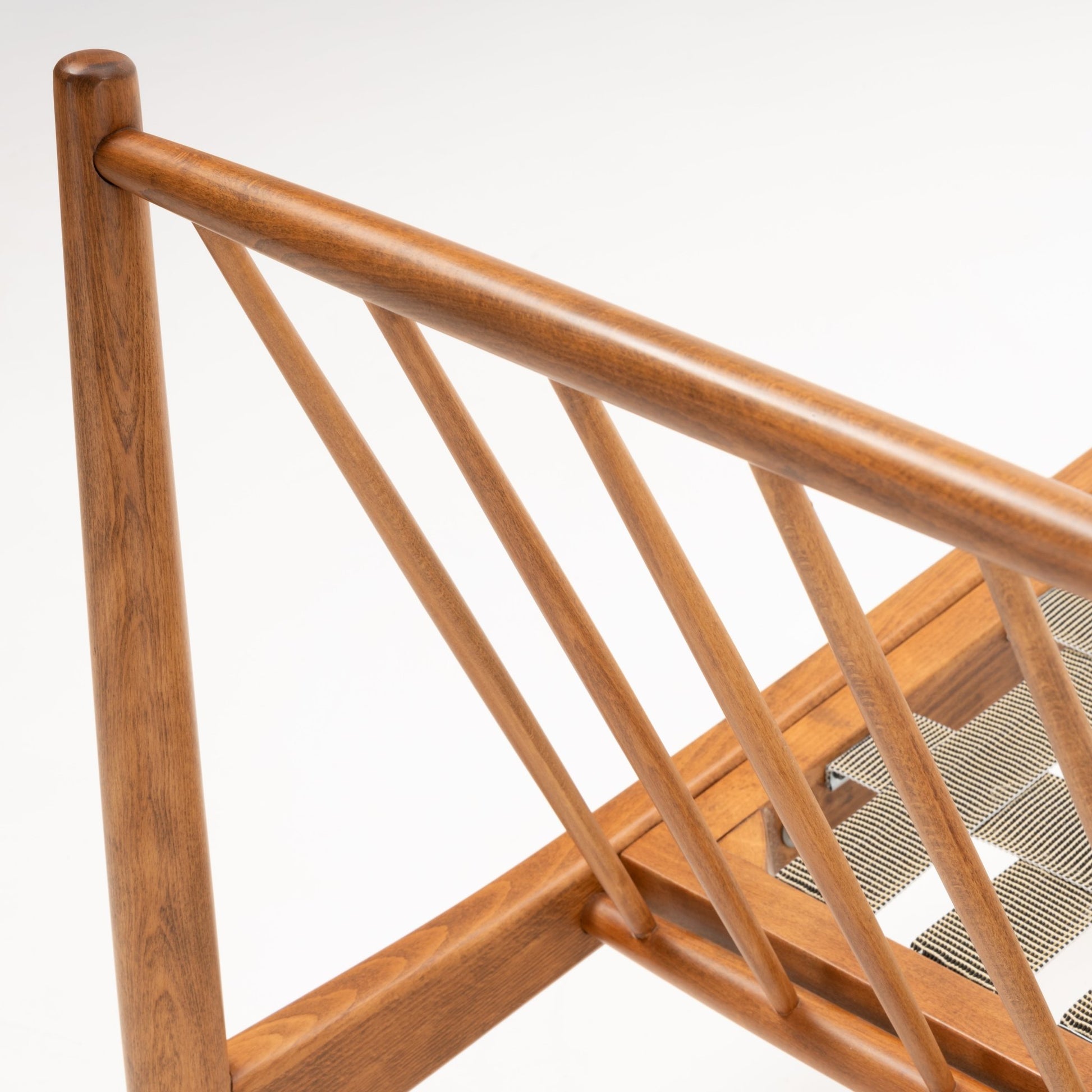 Close-up angled view of Folke Ohlsson slipper chair frame highlighting slanted beechwood spindles and woven seat support