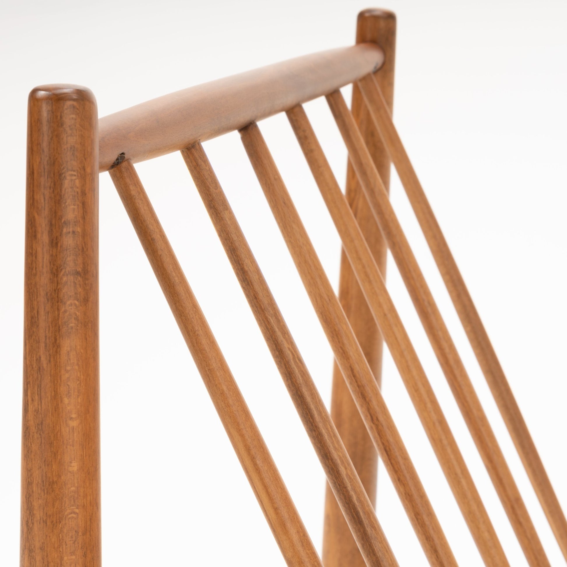 Close-up of Folke Ohlsson slipper chair showing angled beechwood frame with slender vertical spindles and smooth rounded posts