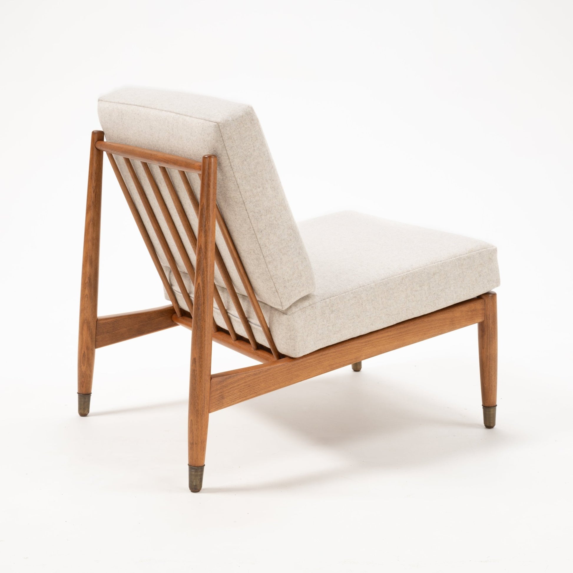 Armless Folke Ohlsson slipper lounge chair with beige cushions and slatted teak and beechwood frame on white background
